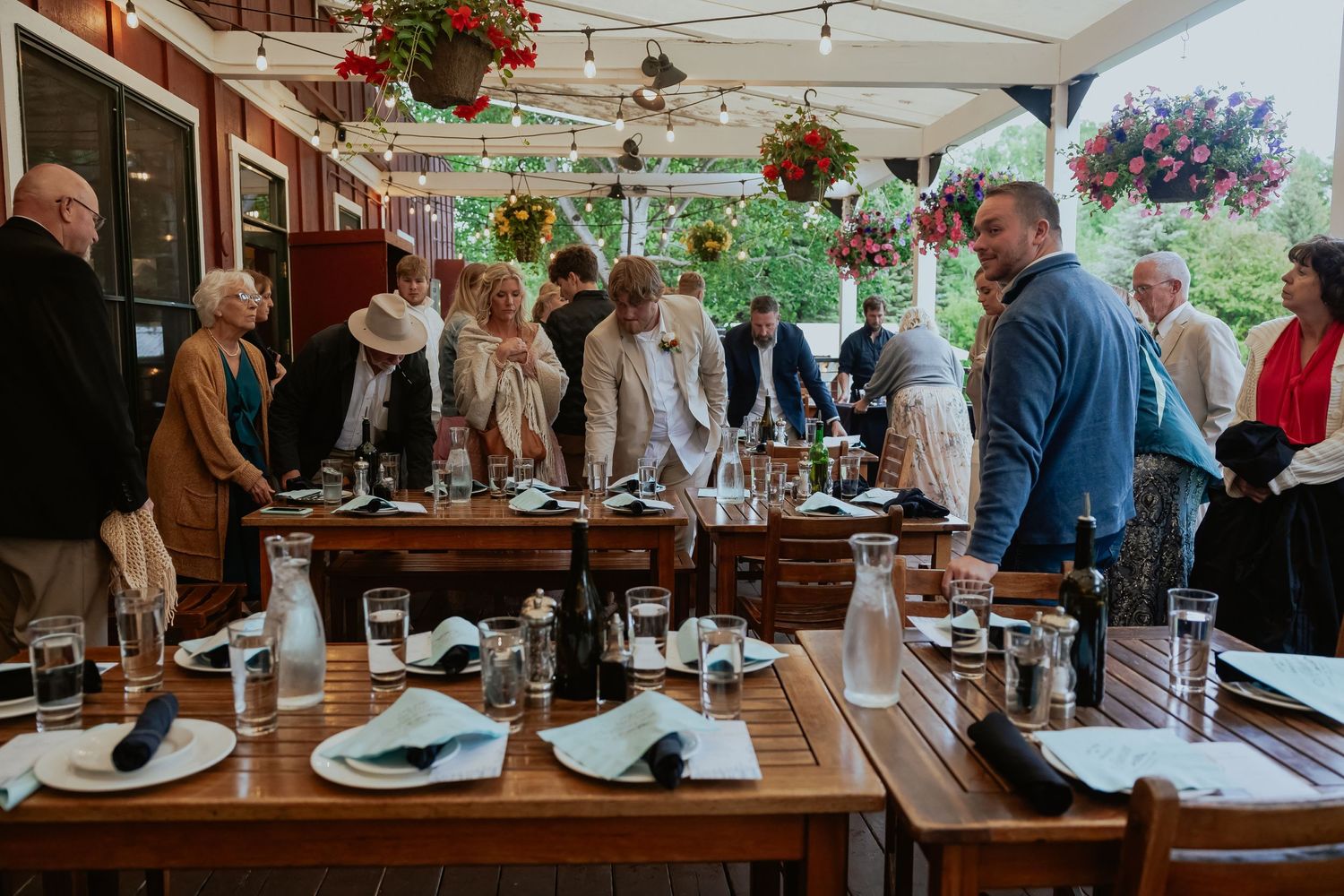 Wedding reception guests mingle and socialize at tables decorated with hanging floral arrangements.