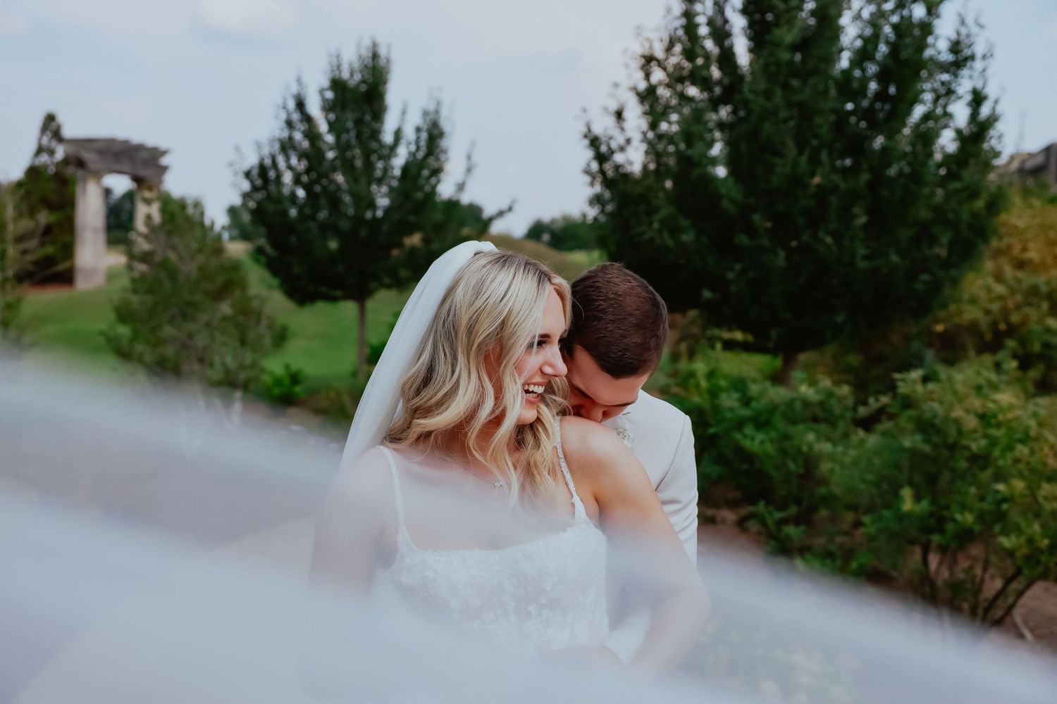 Romantic couple shares intimate moments in an outdoor garden setting with lush greenery and natural light. Candid wedding detail shot
