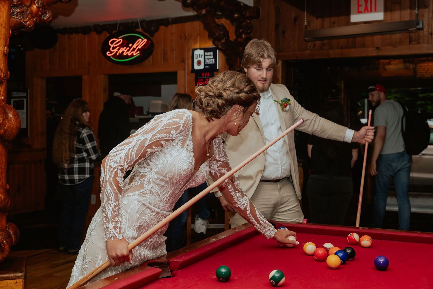 A couple plays pool together at a rustic venue during a wedding celebration.