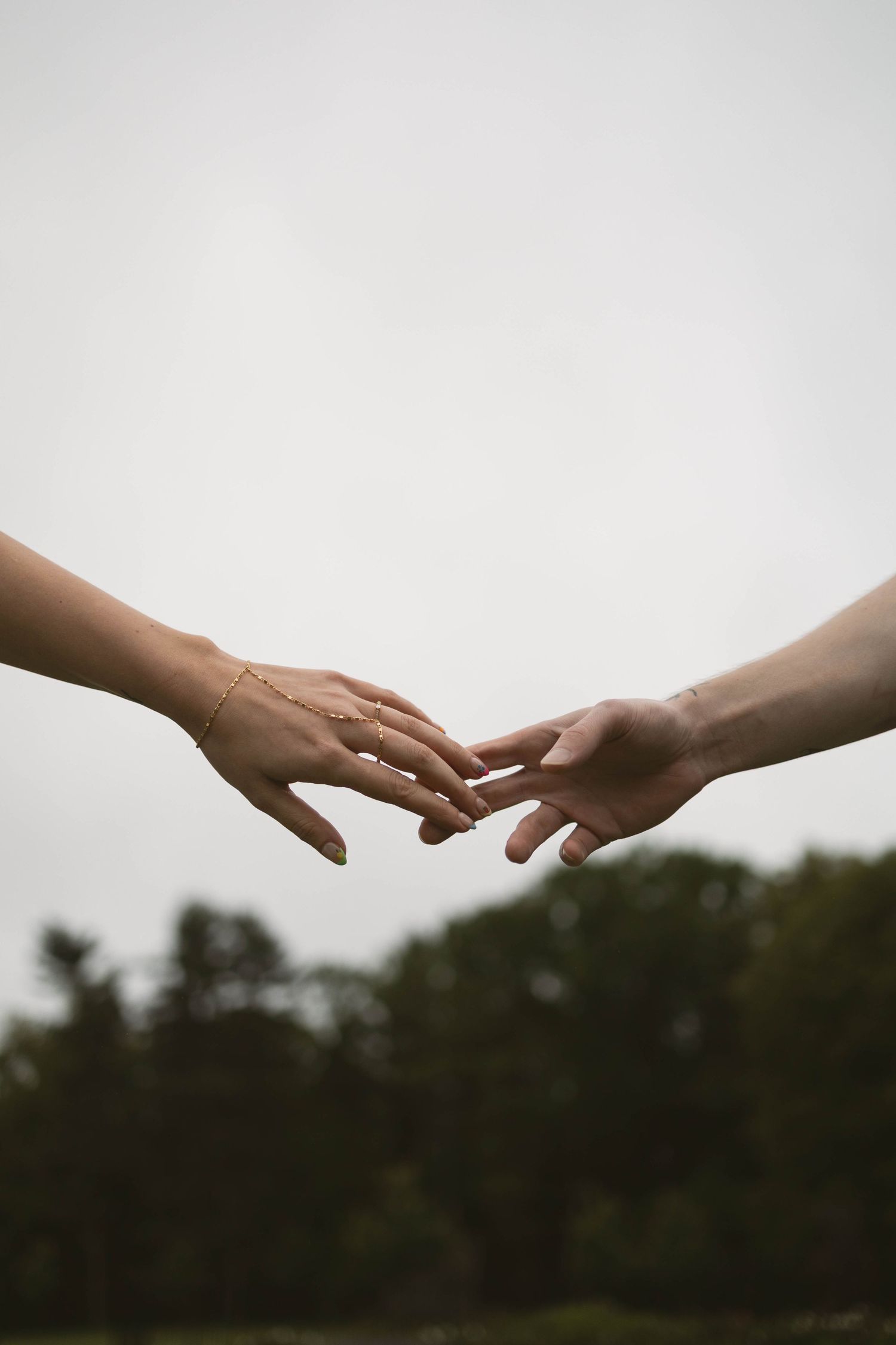 Two hands reaching towards each other against a blurred green nature background in sequence motion photography.