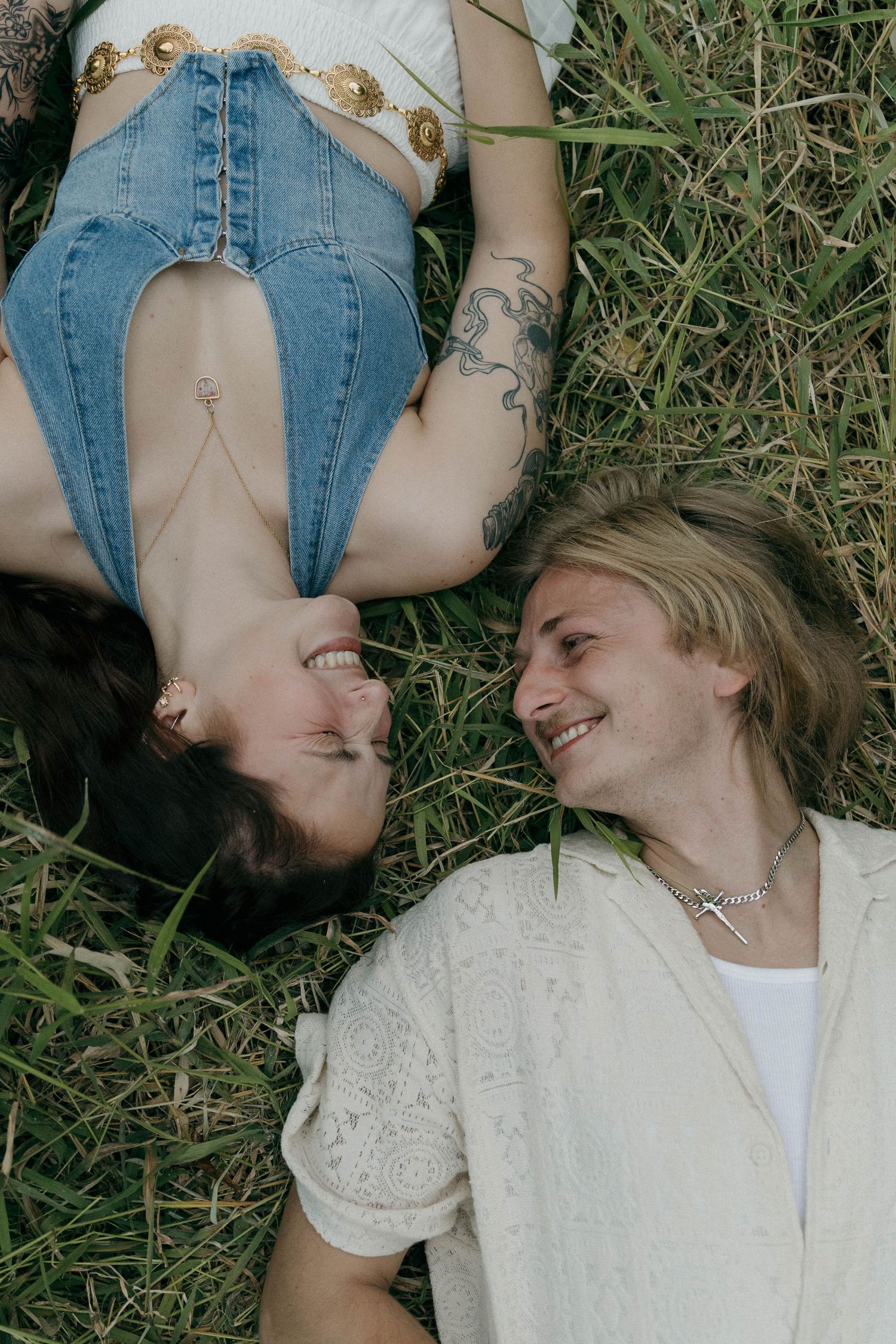A series of candid photos showing two people lying in grass wearing denim and white clothing while laughing together.