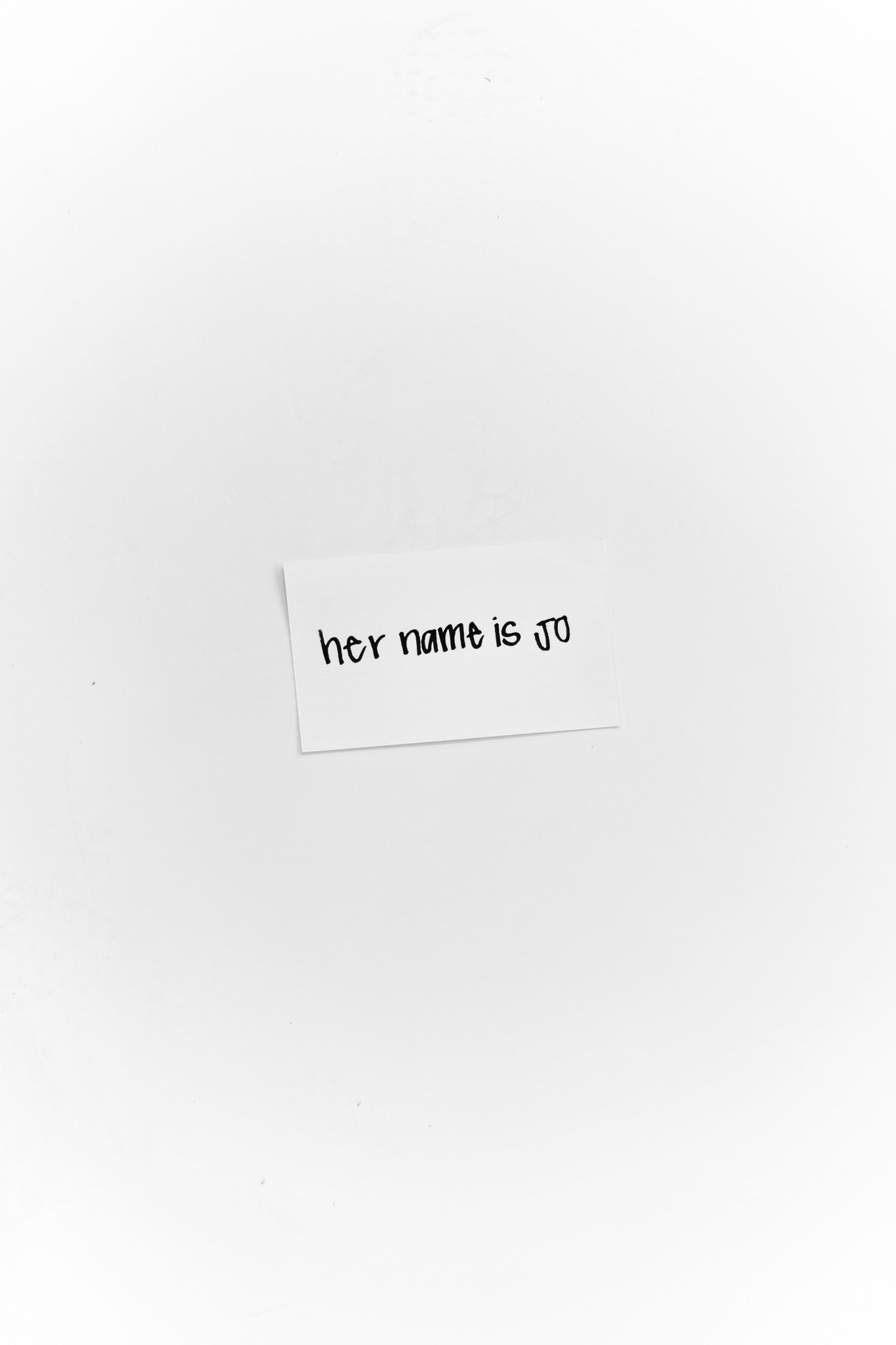Handwritten note on white paper reading 'her name is jo' in simple black text.