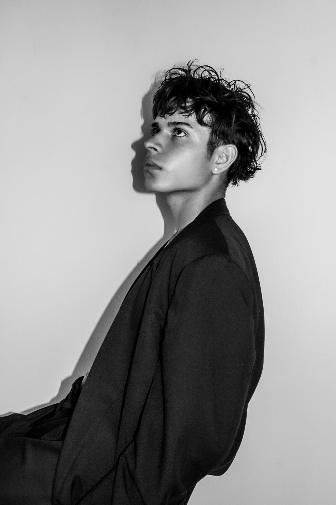 A dramatic black and white portrait showing a profile view of someone in a dark blazer.