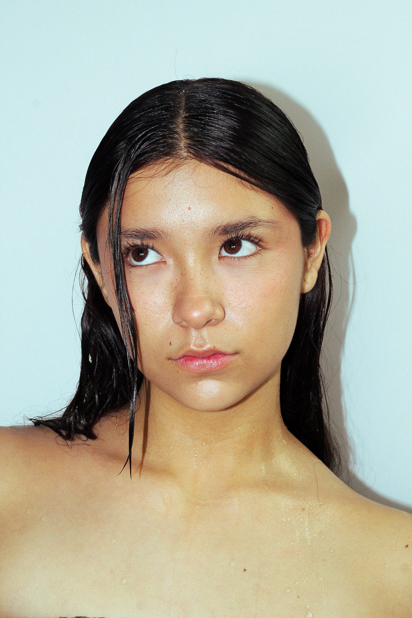 Beauty portrait of a model with wet hair against light blue background.