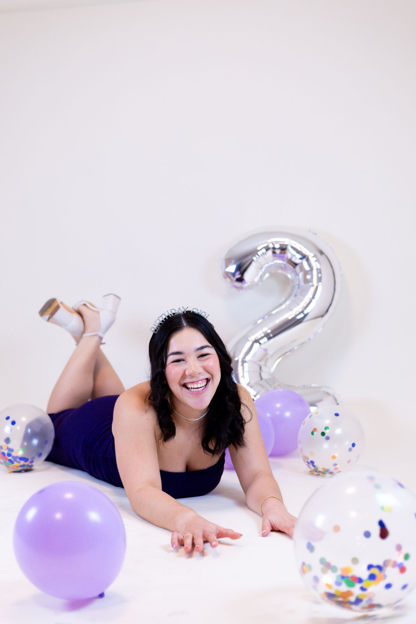 Joyful scene with purple and clear balloons, confetti, and white background creating a festive celebratory atmosphere.