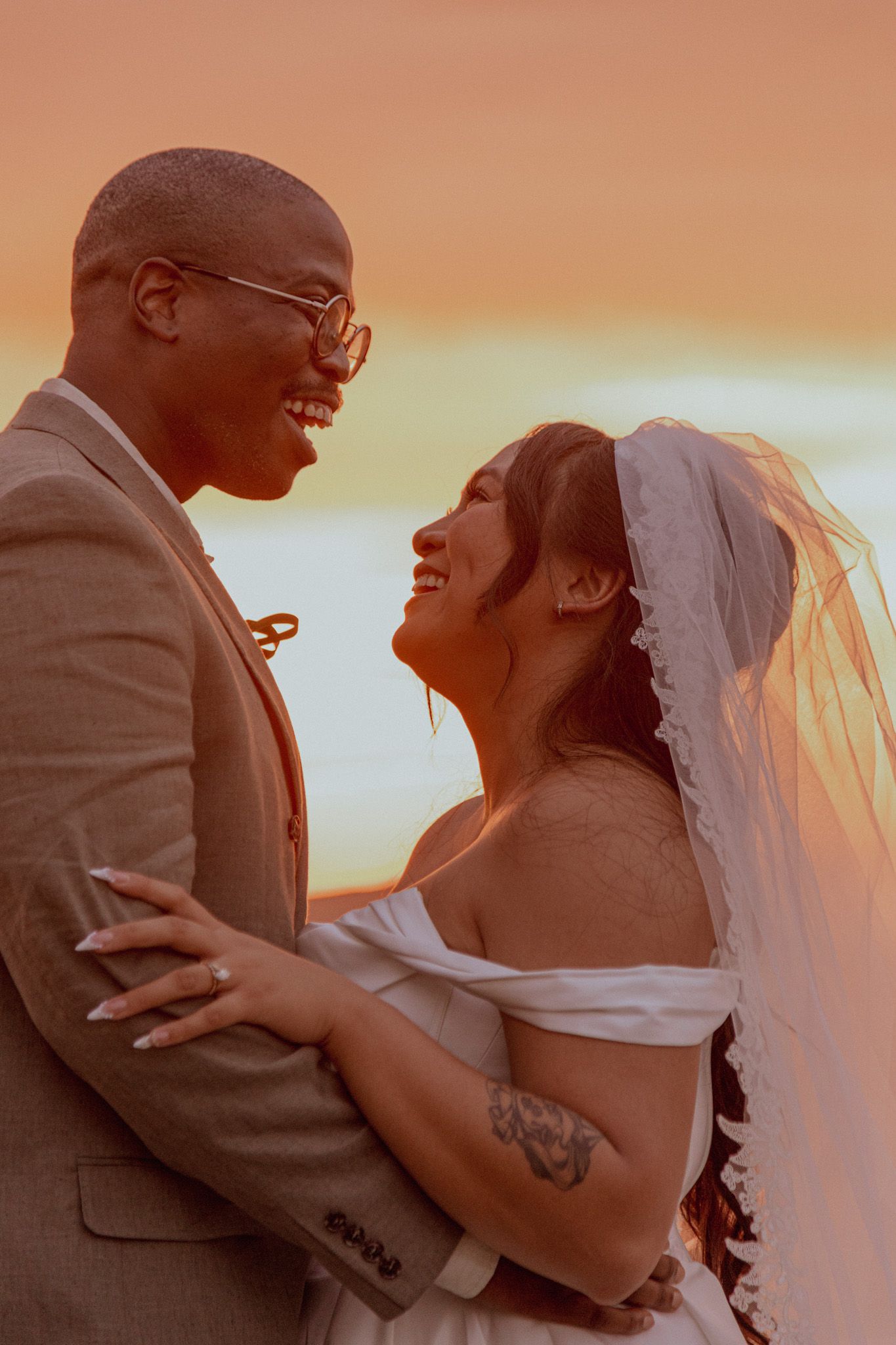 Romantic silhouette of a couple embracing during golden sunset at their wedding.