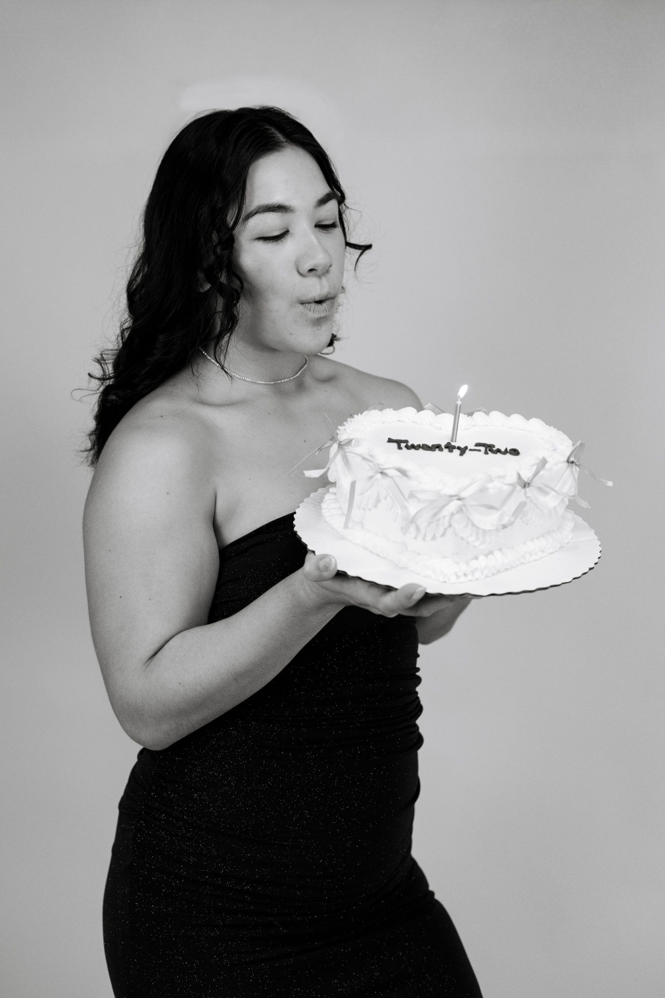 A series of black and white photos showing someone in a black dress blowing flour or powdered sugar into the air.