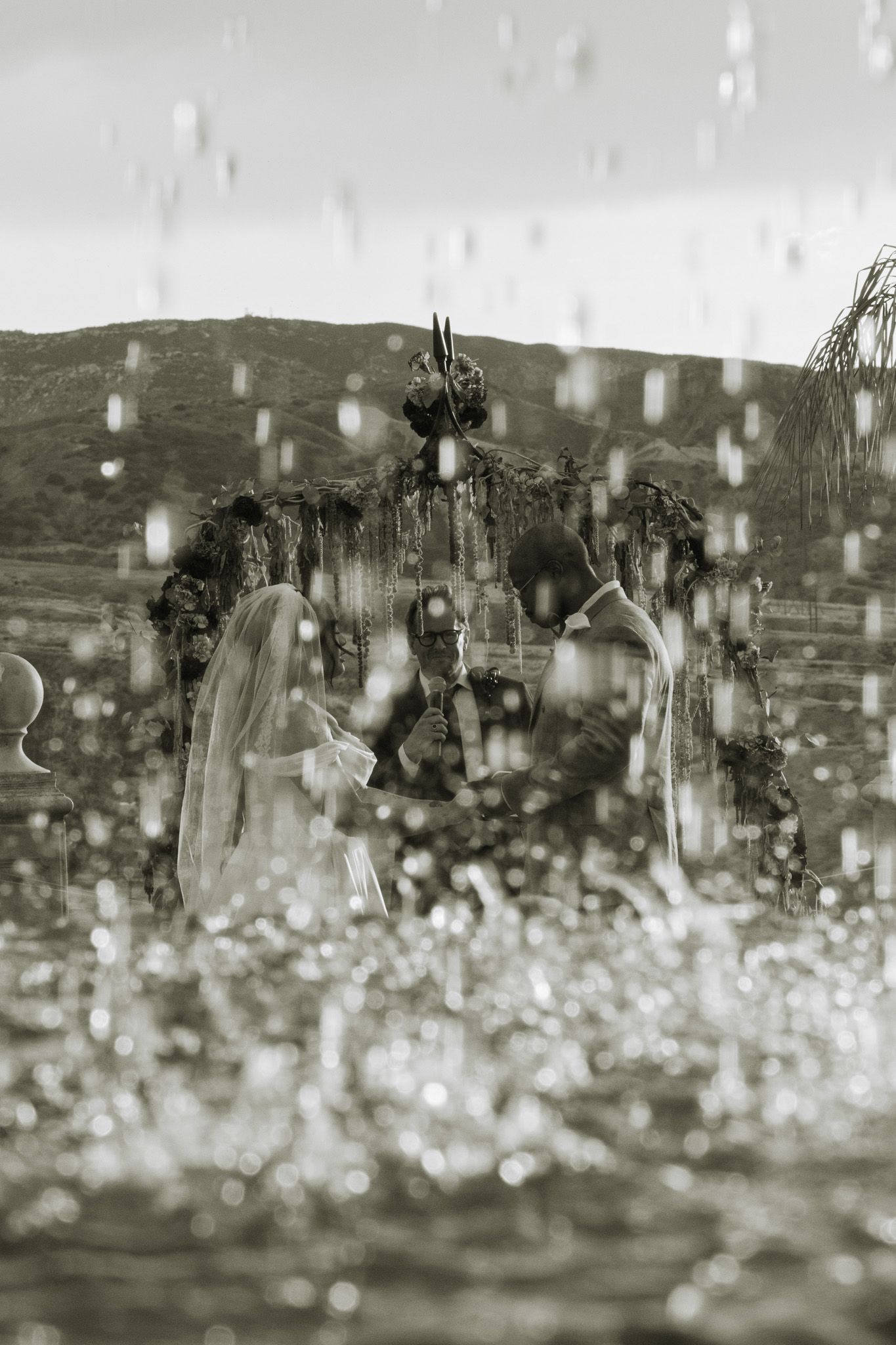 Rain drops falling in slow motion create a blurred bokeh effect against a dark background.