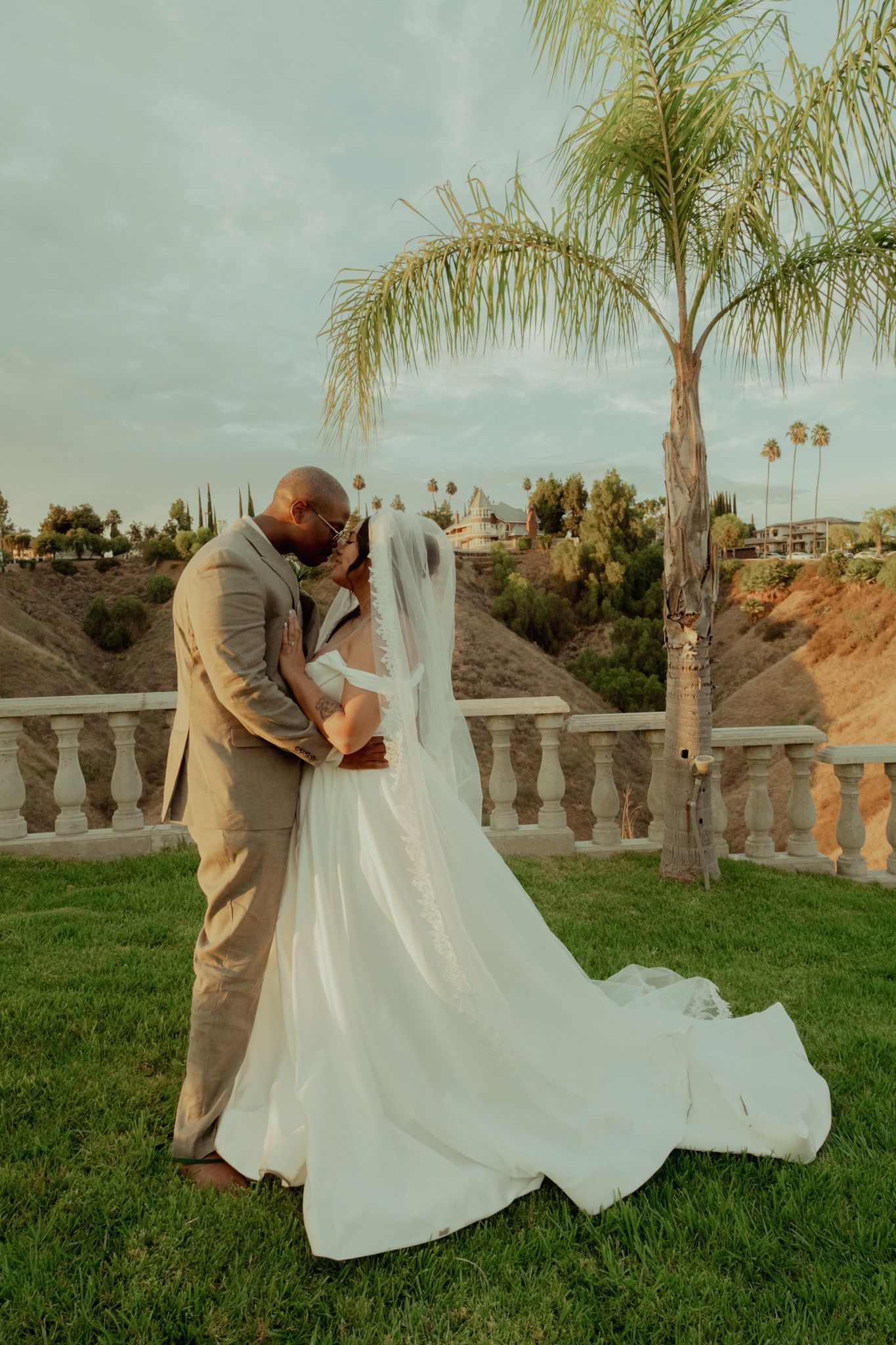 A romantic wedding moment captured in a series of four photos showing a couple embracing on a grassy lawn with palm trees.