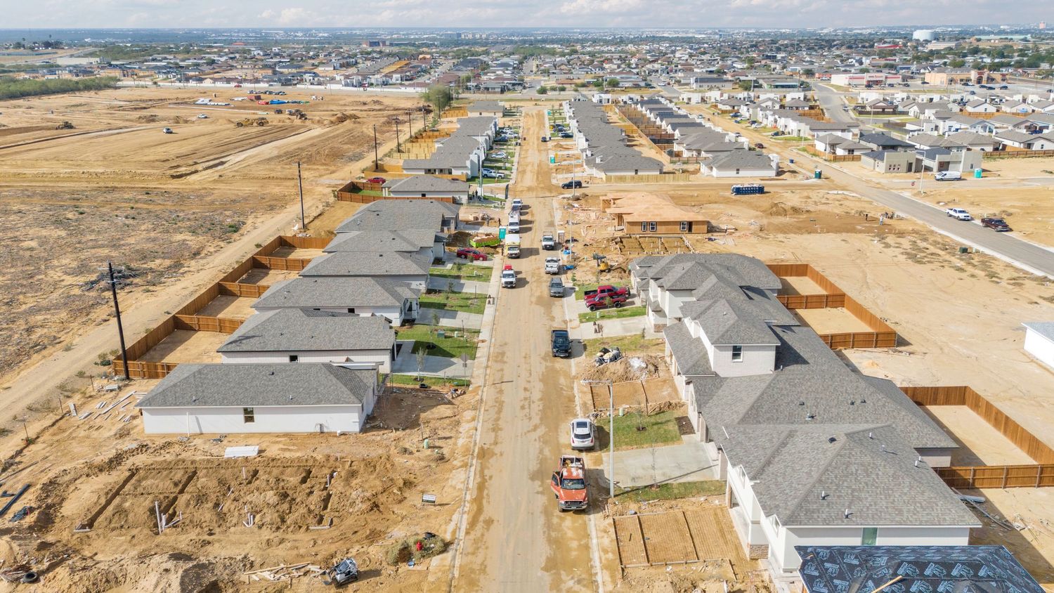Wide aerial view of a housing development under construction showing new roads and partially built homes.
