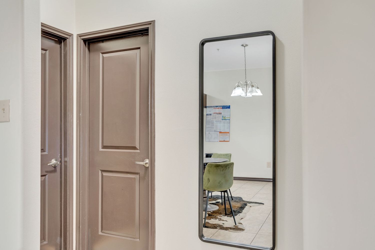 Modern apartment hallway with light brown doors, white walls, and pendant lighting fixtures.