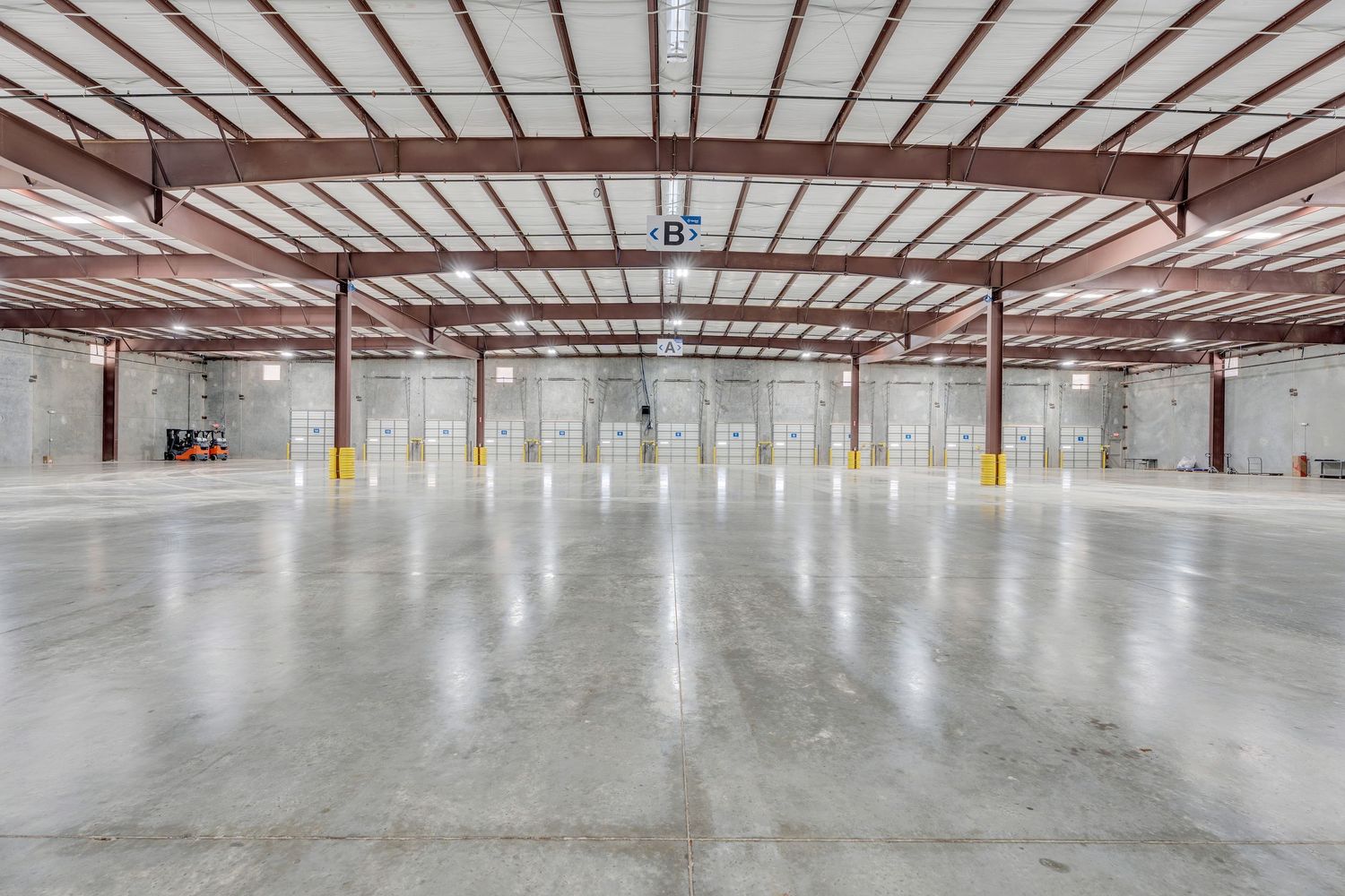 Construction progress photos show a large empty warehouse interior with concrete floors and metal ceiling beams.