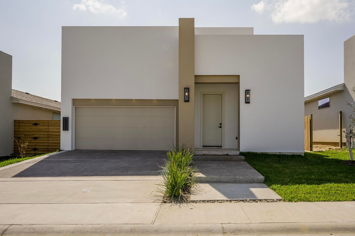 Modern minimalist white house with flat roof and two-car garage.