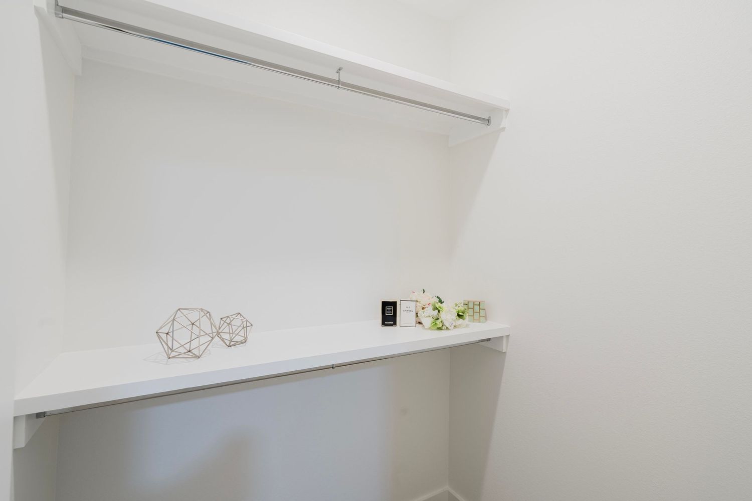 Clean white closet interior with built-in shelving and minimal decorative elements.