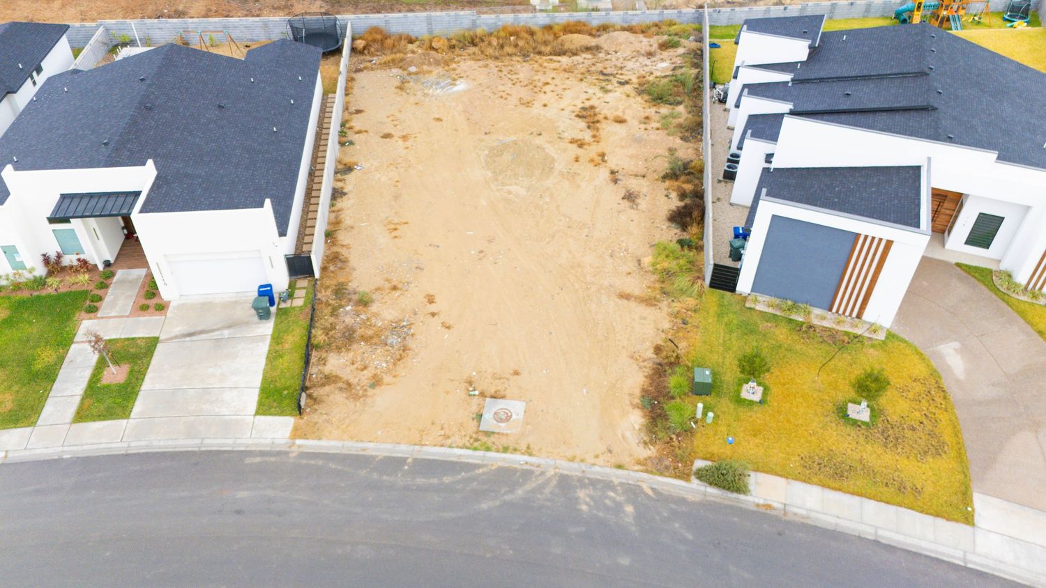 Aerial panoramic view of a residential construction site with dirt plots and paved roads.