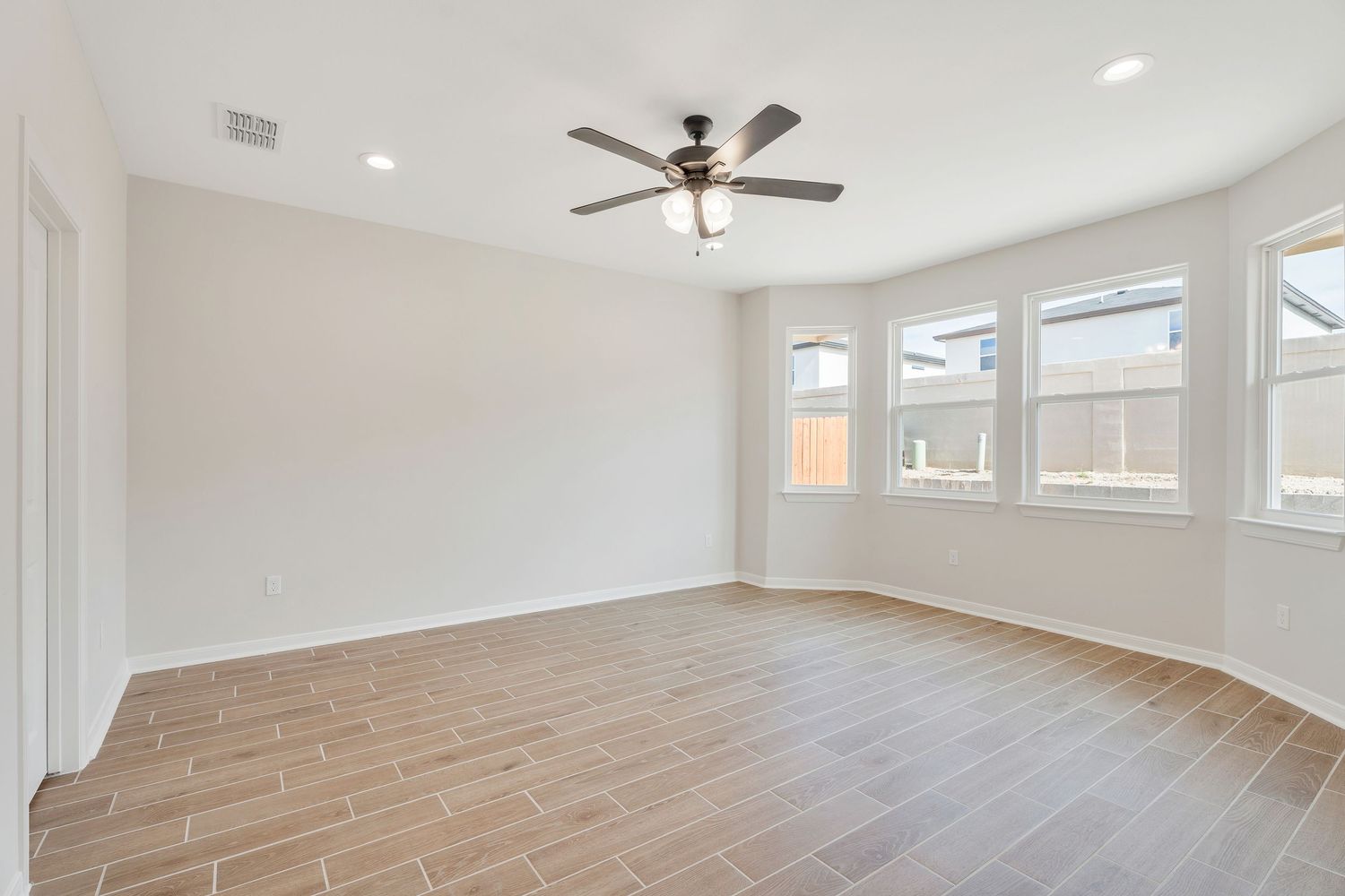 Modern living room interior with white walls, hardwood floors, and large windows letting in natural light.