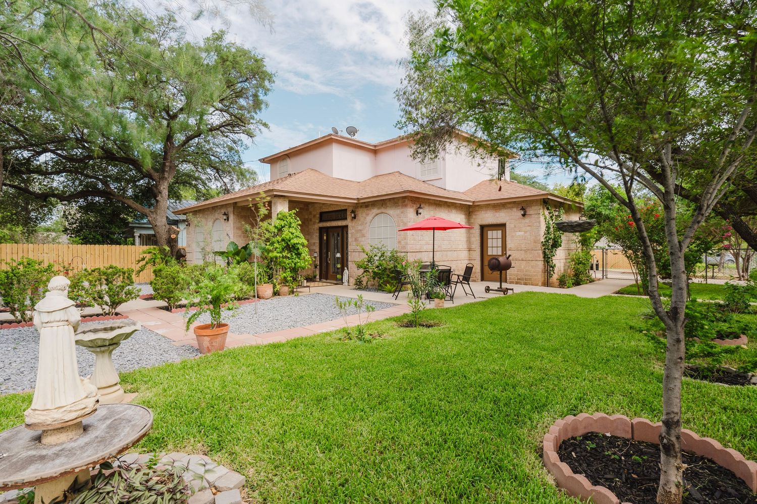 A panoramic view of a residential backyard showing green lawn, trees, and neighboring houses on a sunny day.
