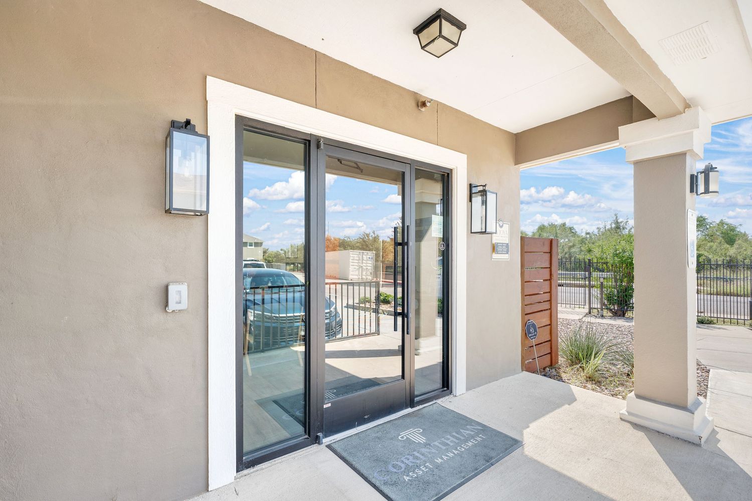 Modern apartment balcony with sliding glass doors and beige exterior walls.