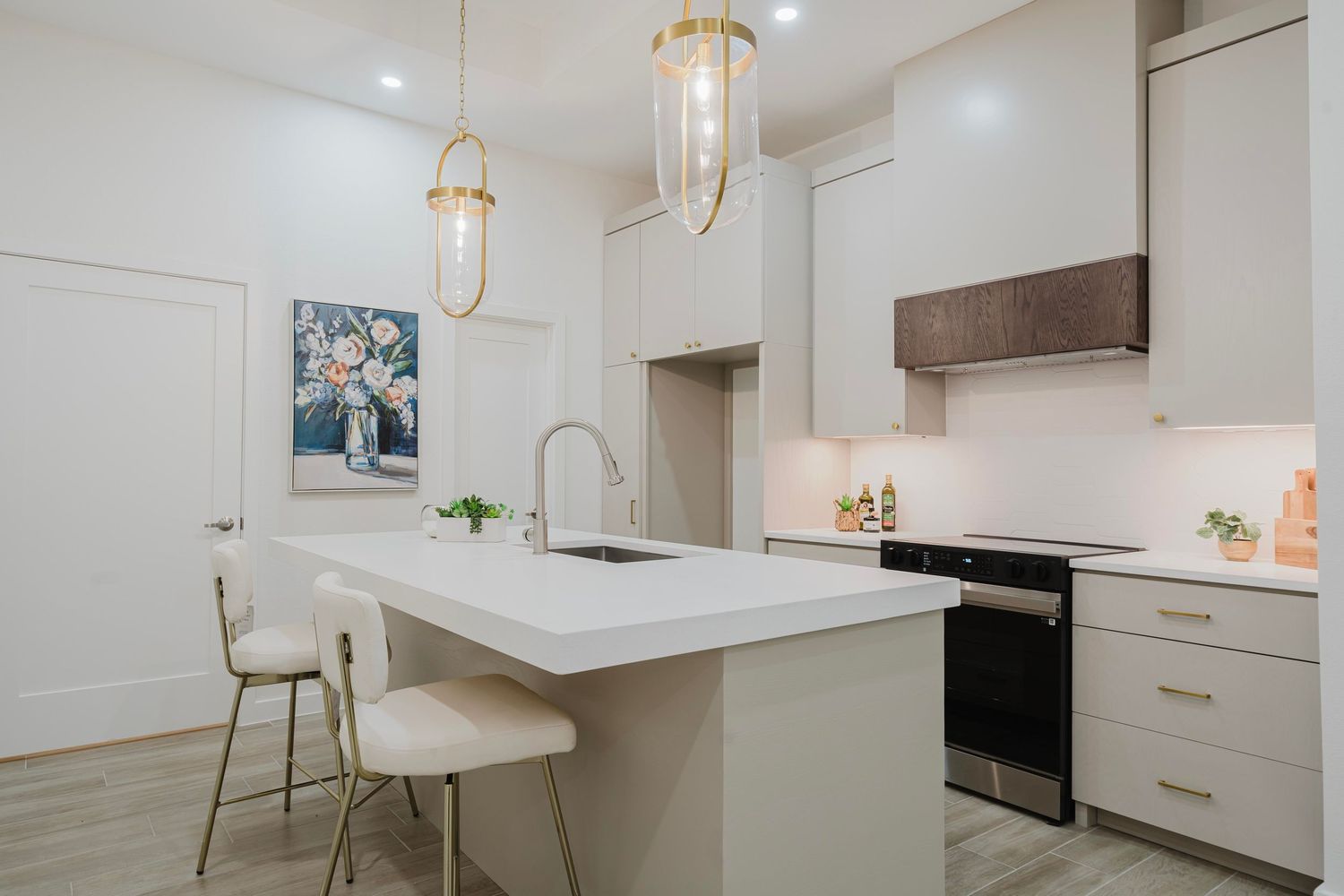 Modern white kitchen with pendant lights, waterfall countertop, and minimalist white cabinetry.
