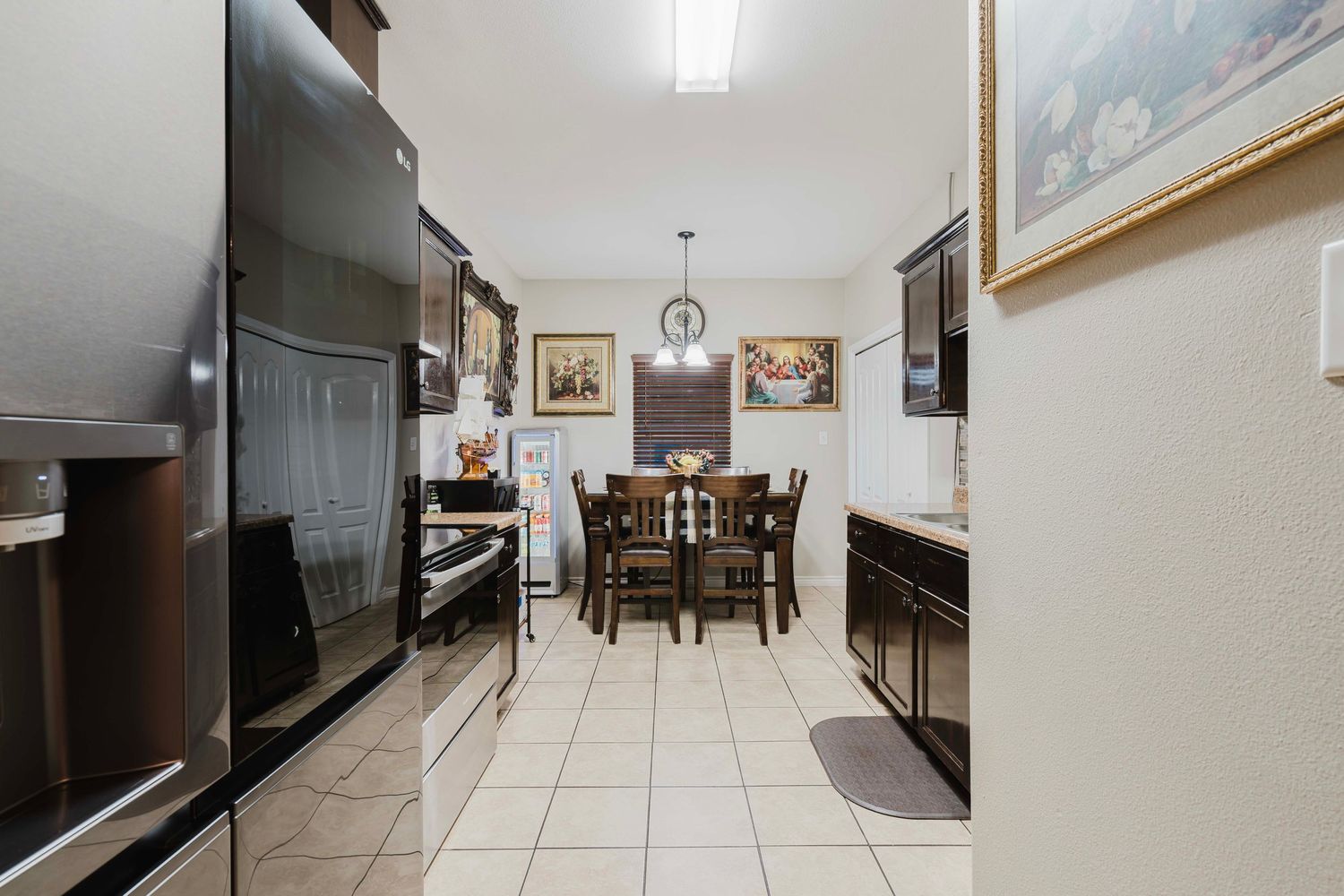 Modern kitchen with dark appliances, tile flooring and a dining area visible at the far end.