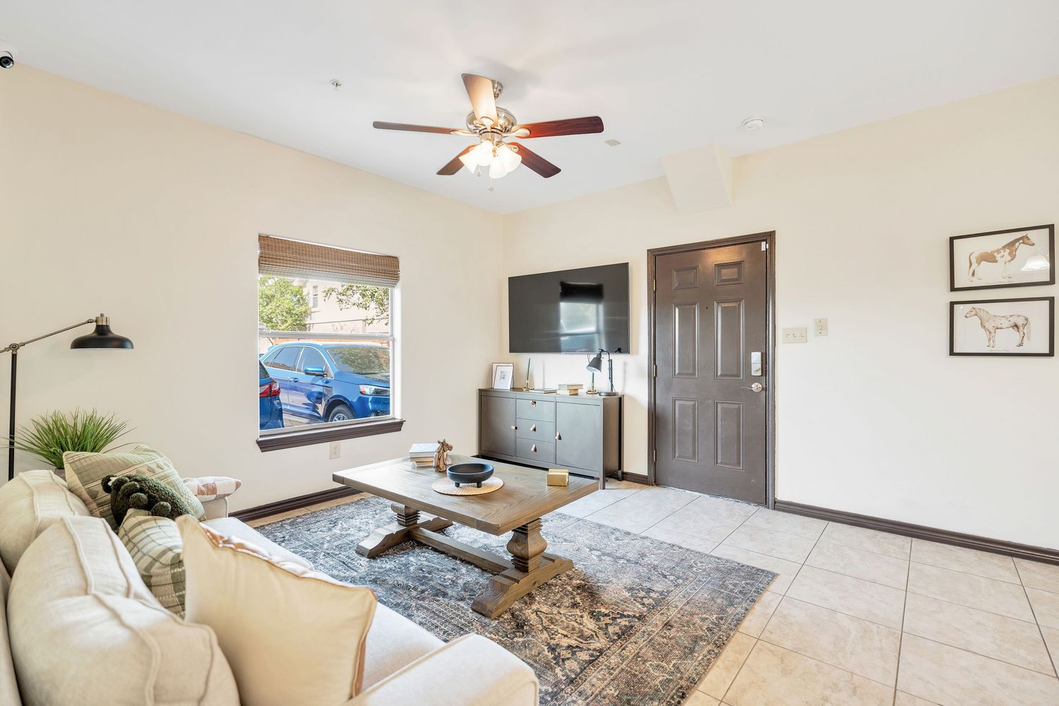 Modern living room interior with ceiling fan, beige walls, and hardwood floors.