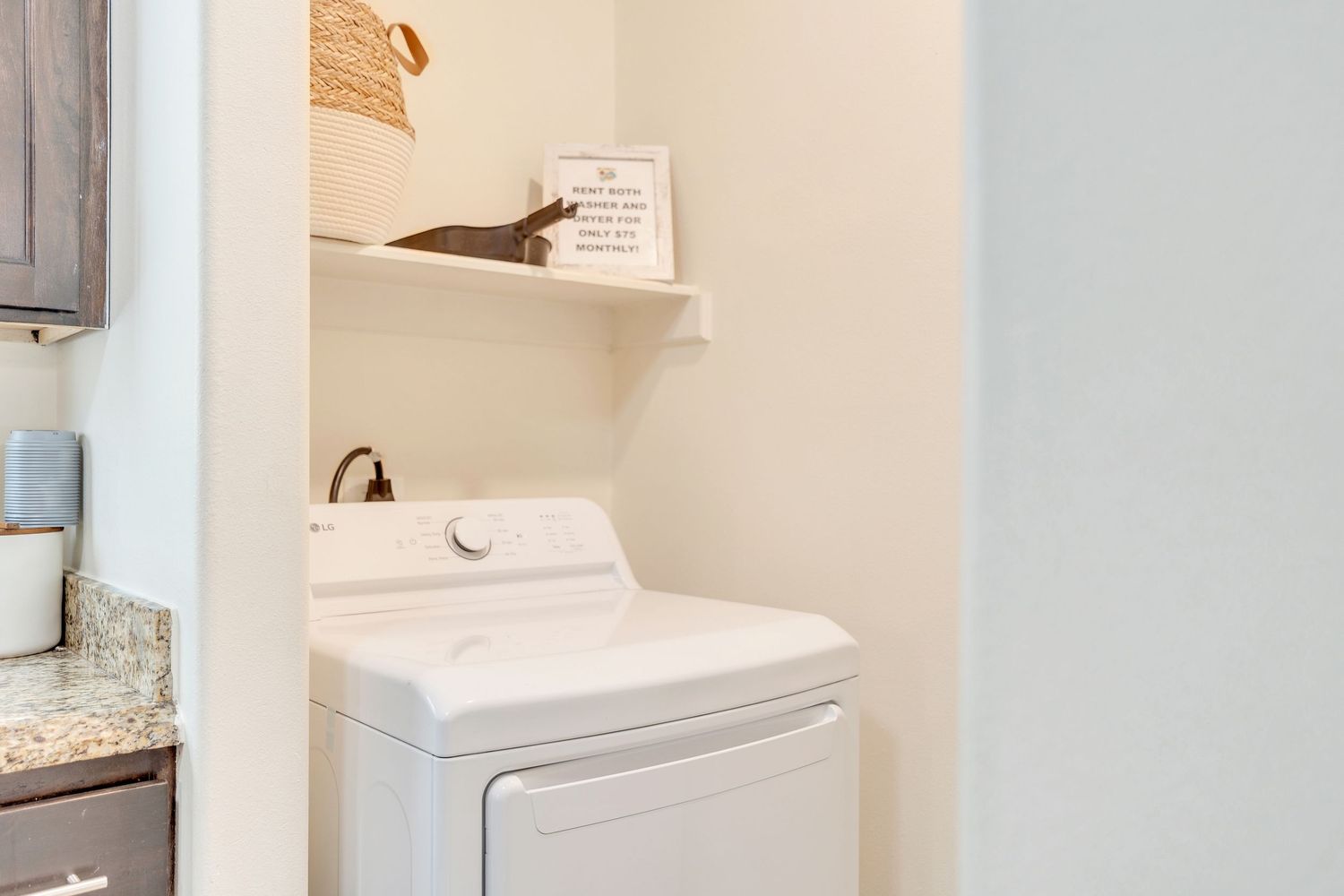 White laundry room interior with washer and dryer, storage shelves, and built-in cabinets against light walls.