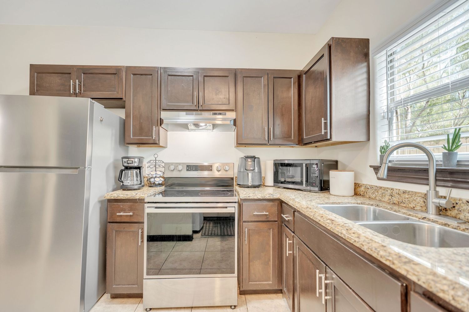 Spacious kitchen featuring brown cabinets, granite countertops, and stainless steel appliances.