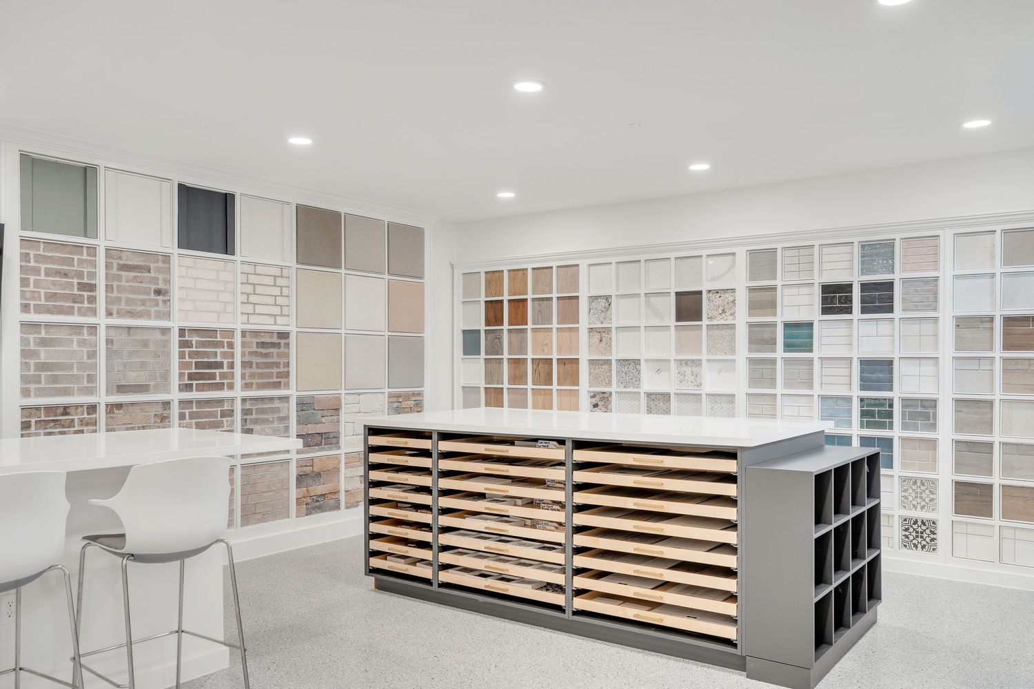 Modern showroom displays tile samples and flooring materials with bright lighting and clean white walls.