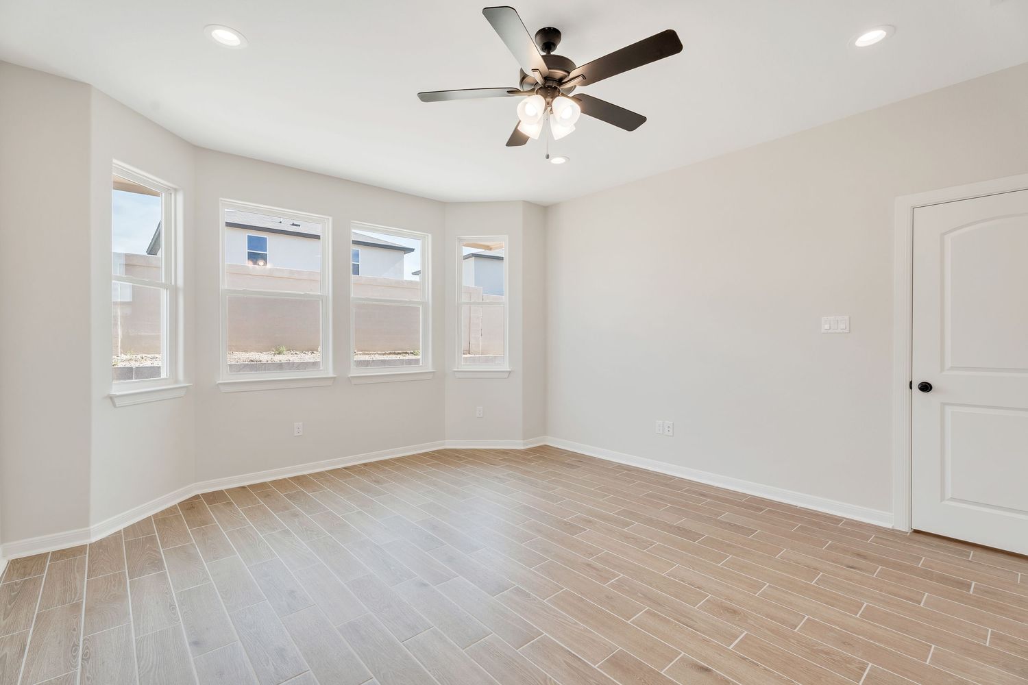 Modern open concept living room with recessed lighting, ceiling fan, and light wood laminate flooring.
