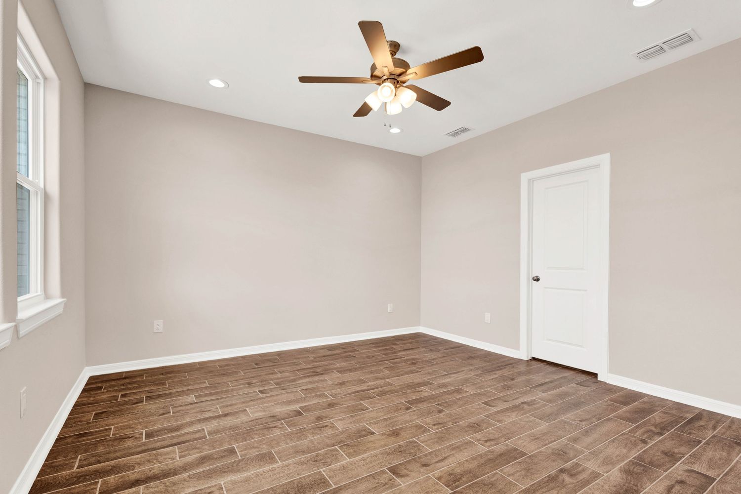 Empty bedroom with wood-look flooring, ceiling fan, recessed lighting, and neutral beige walls in a new construction home.
