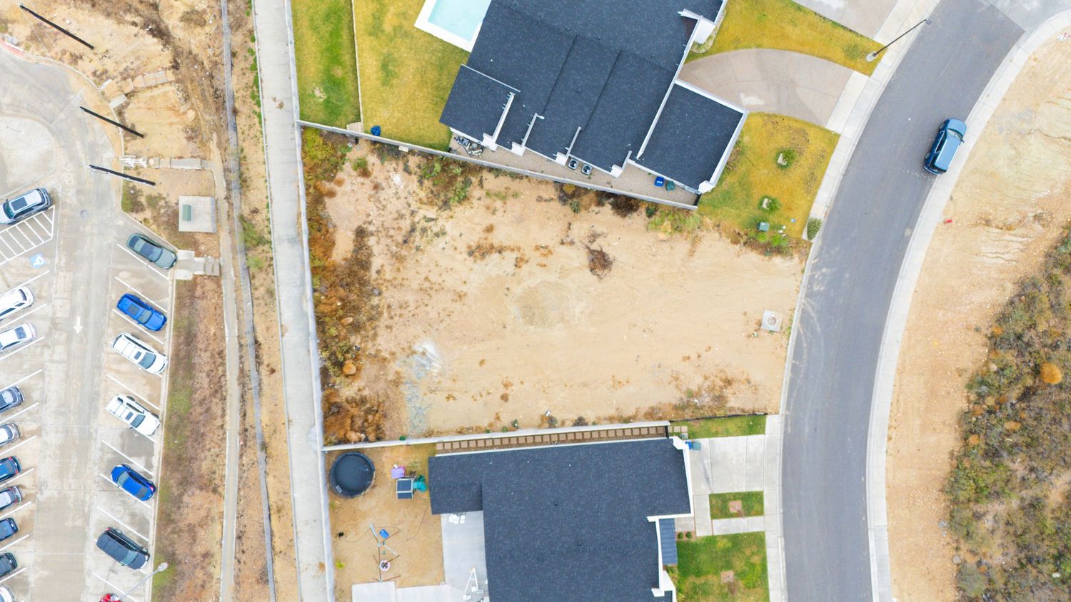Aerial view of a winding residential street with houses and driveways in a suburban neighborhood.