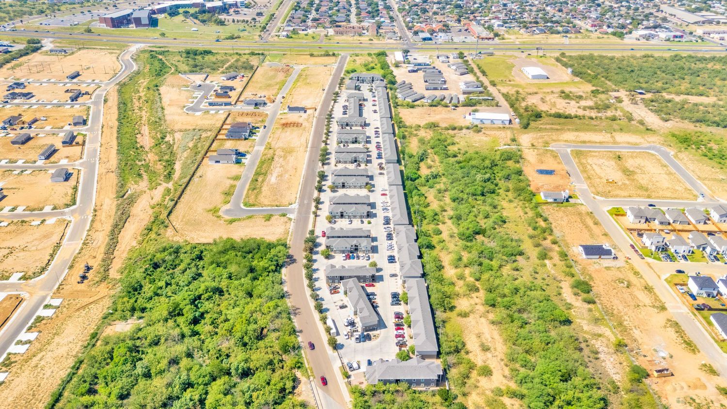 Aerial panorama of a suburban development showing roads, buildings, and surrounding landscape.