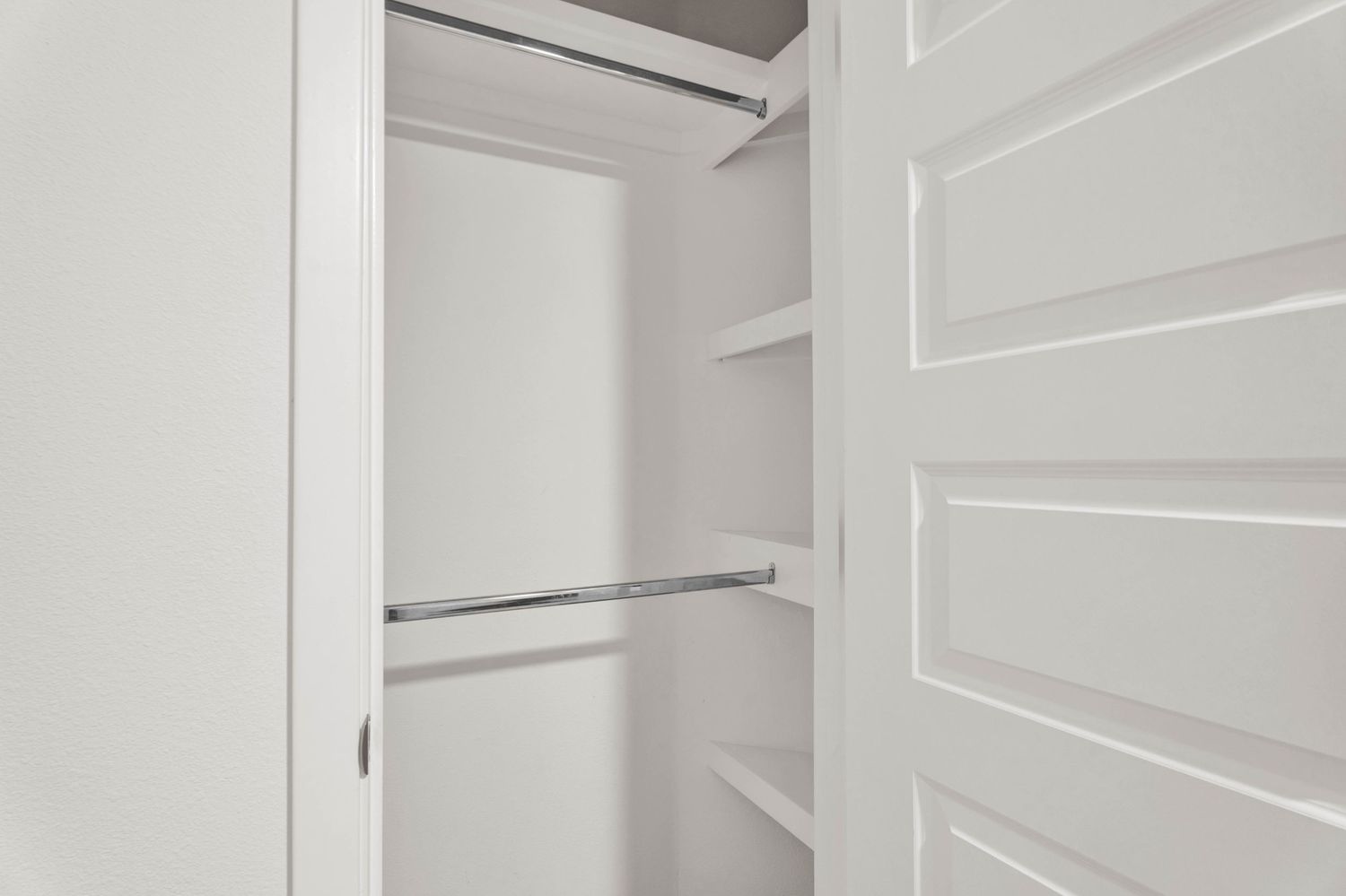 Spacious white walk-in closet with built-in shelving and double hanging rods for ample storage space.