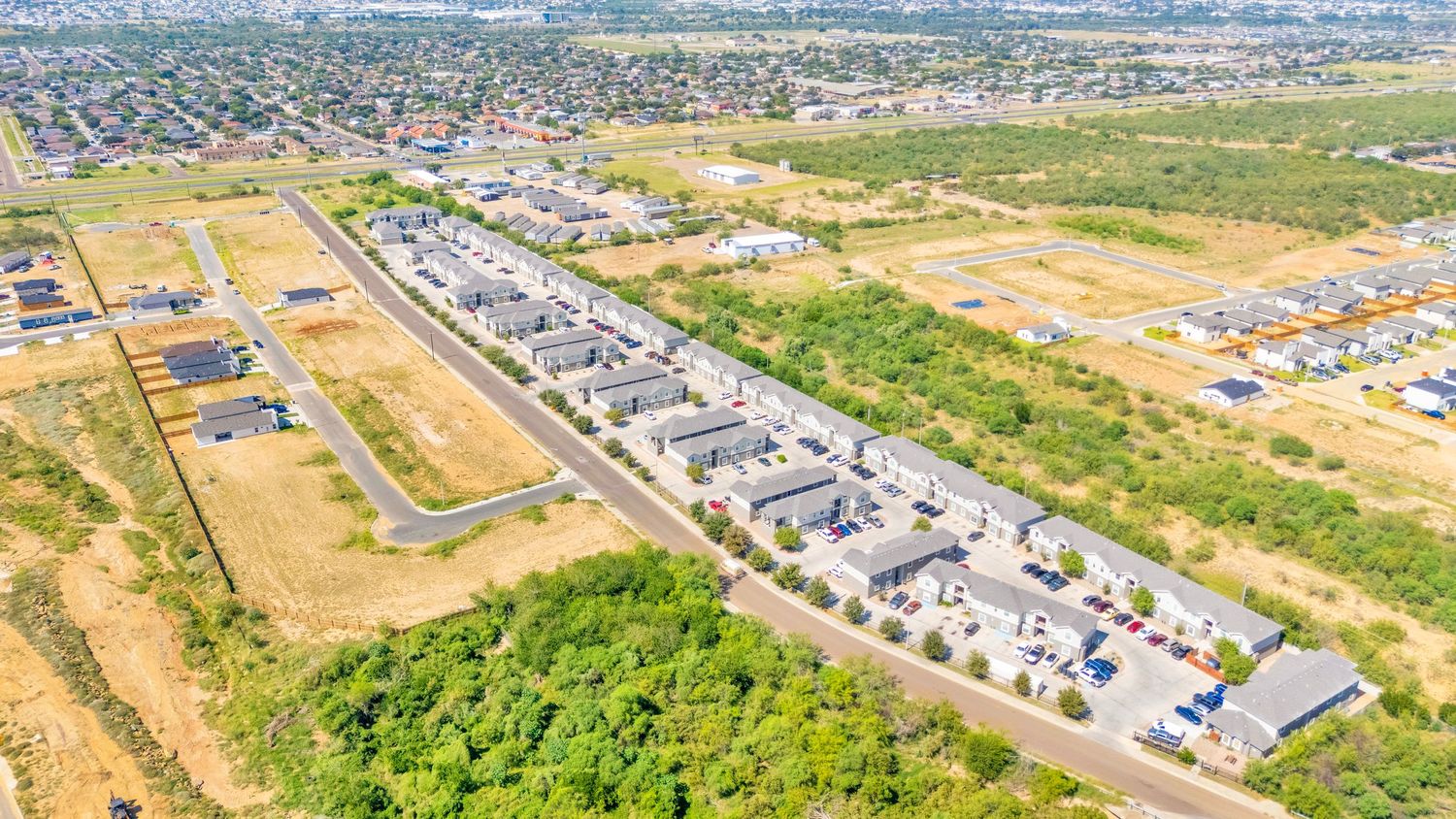 Aerial panorama of suburban residential development with houses and green spaces.