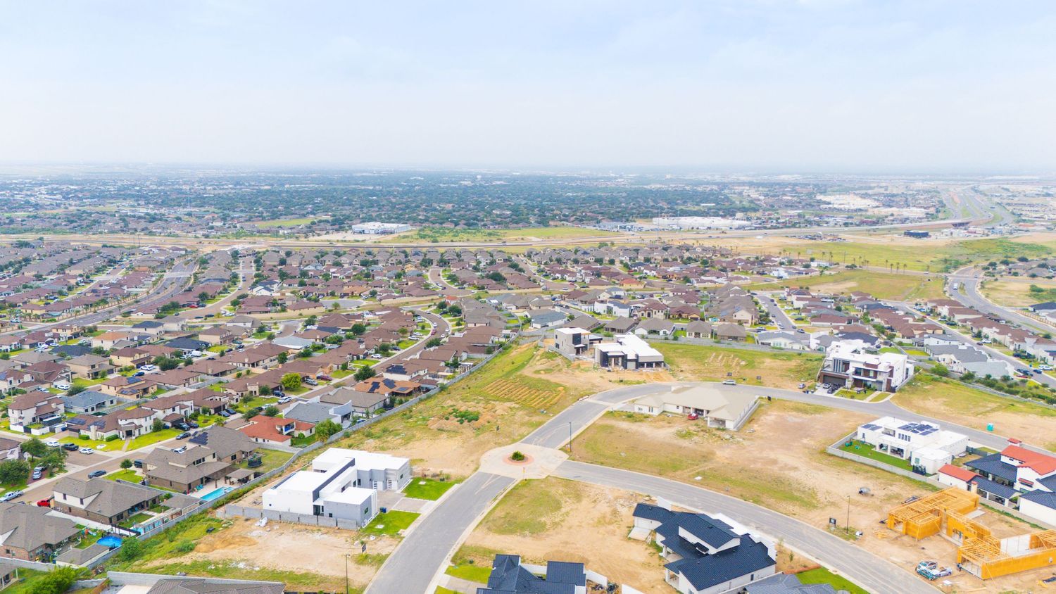 Aerial view showing suburban development and residential construction lots in a growing neighborhood on a clear day.