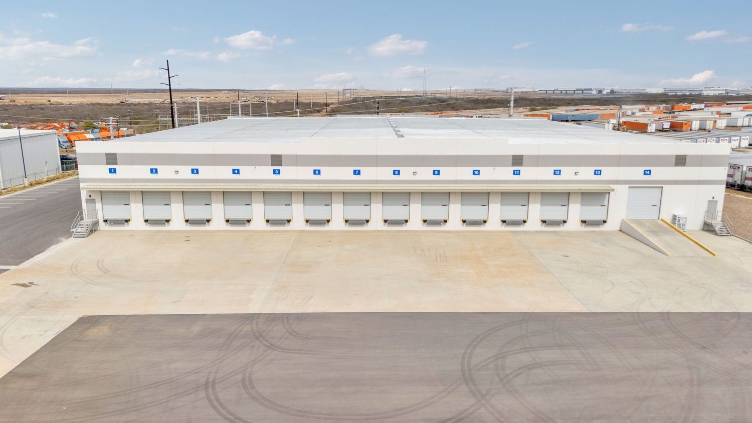A panoramic view of multiple white industrial loading docks and warehouse doors at a distribution facility.