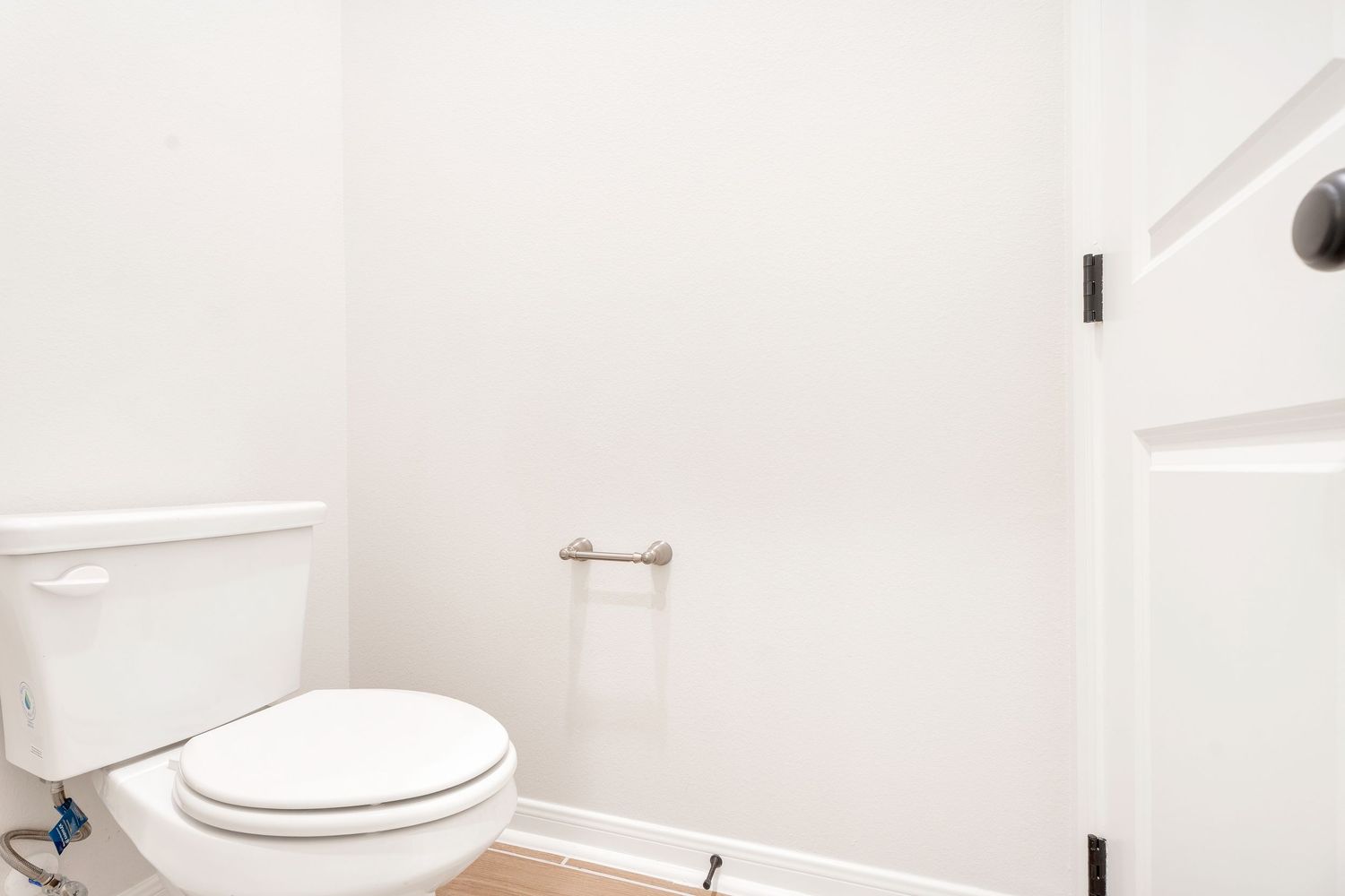 A modern white bathroom interior with a toilet, vanity, and sleek fixtures against clean white walls and flooring.