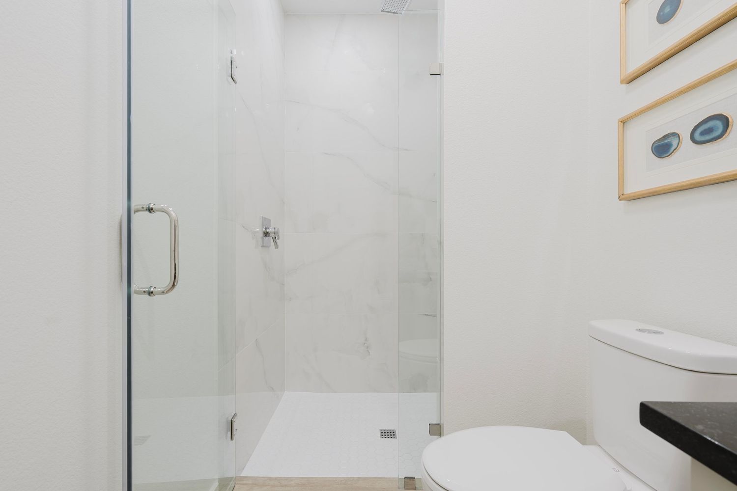 Modern white bathroom featuring a glass shower enclosure and sleek fixtures.