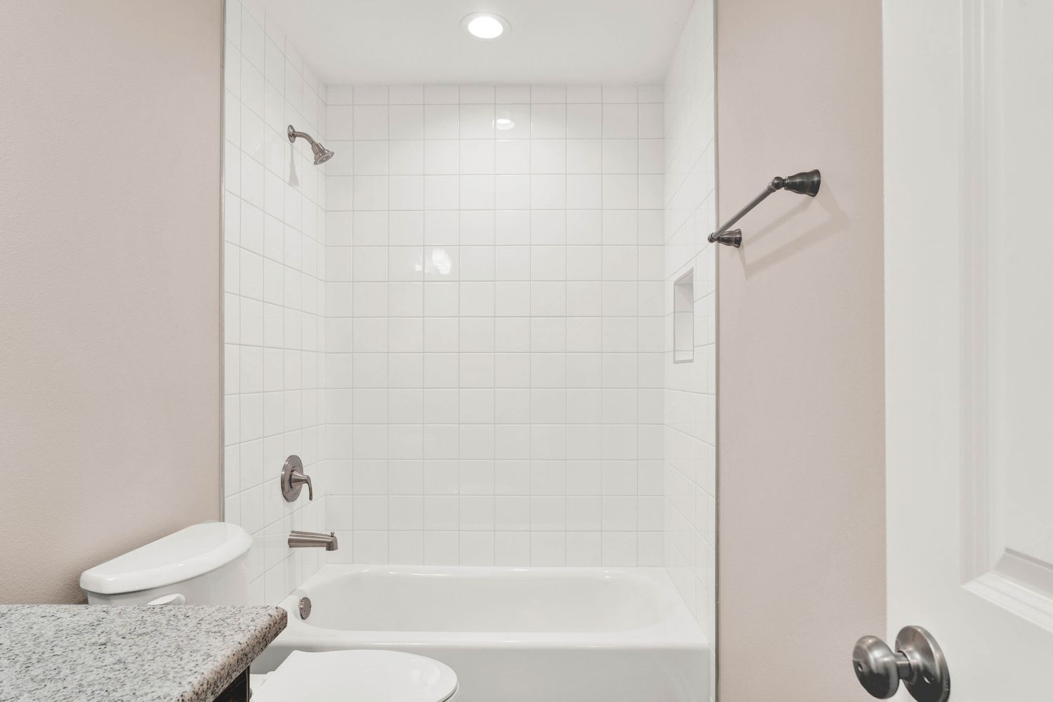 Modern bathroom with white subway tile shower, soaking tub, granite vanity, and brushed nickel fixtures.