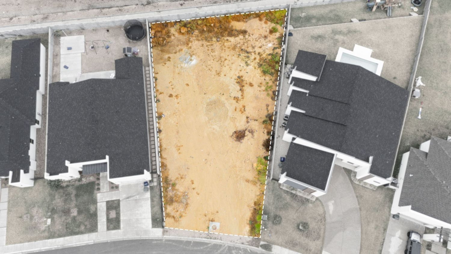 Aerial view of residential neighborhood showing rooftops, driveways and yards from above in suburban setting.