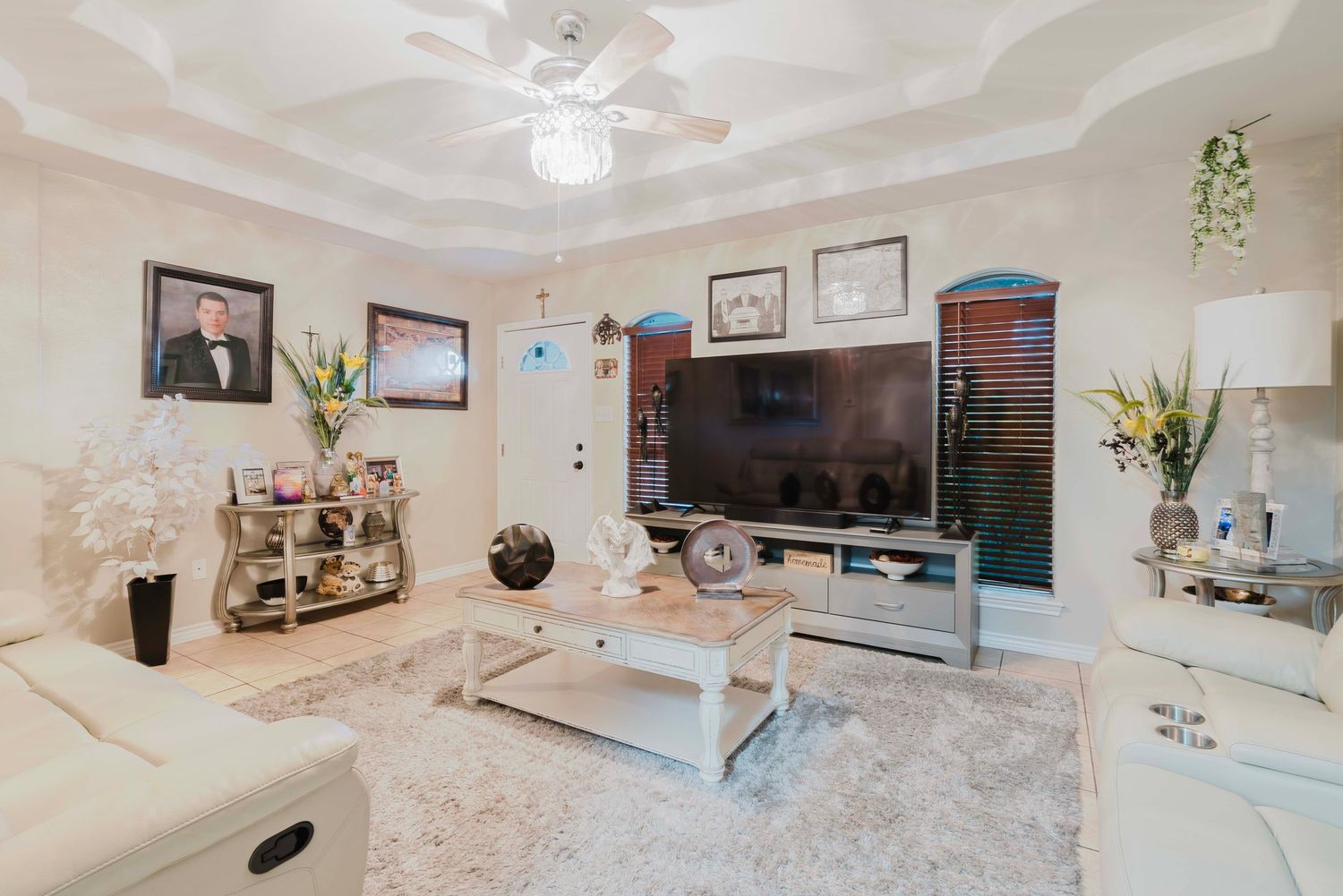 Modern living room with white marble floors, TV mounted on wall, grey sofa, and geometric coffee table.