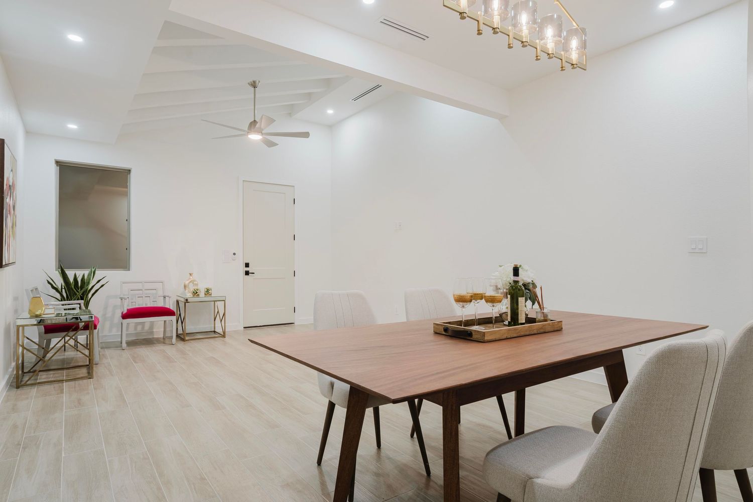 Clean modern dining space with wooden table, white chairs, and contemporary pendant lighting fixture.