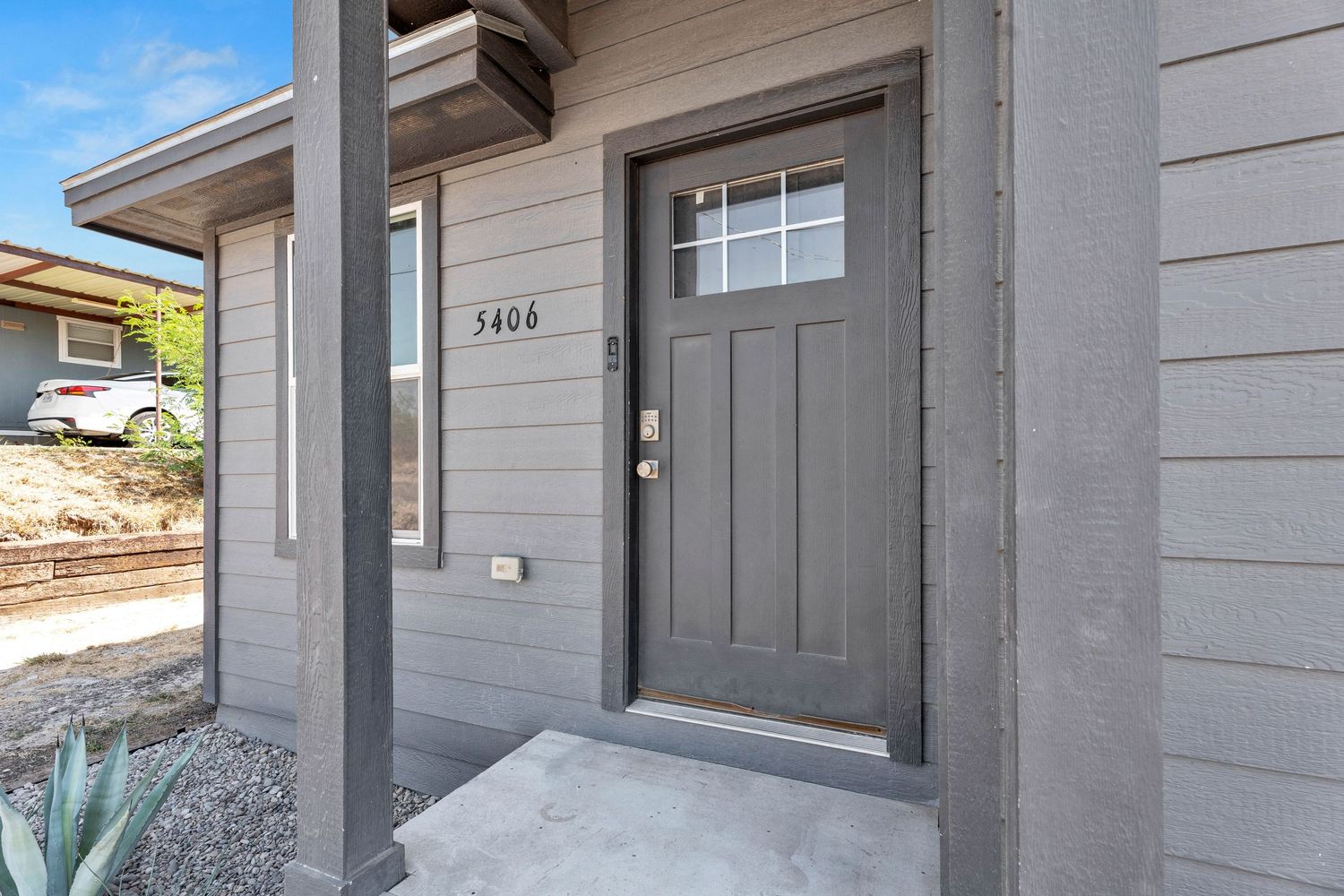 Gray craftsman-style front door with transom window and house number 5406 on a modern home exterior.