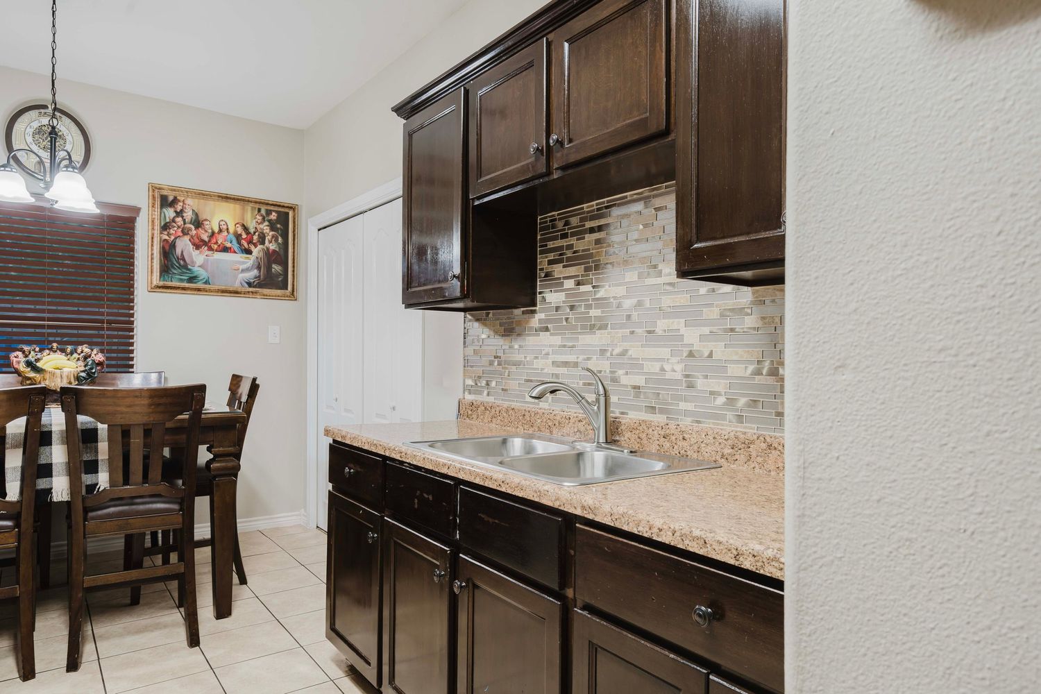 Dark brown kitchen cabinets with granite countertops and stone backsplash in galley-style layout.