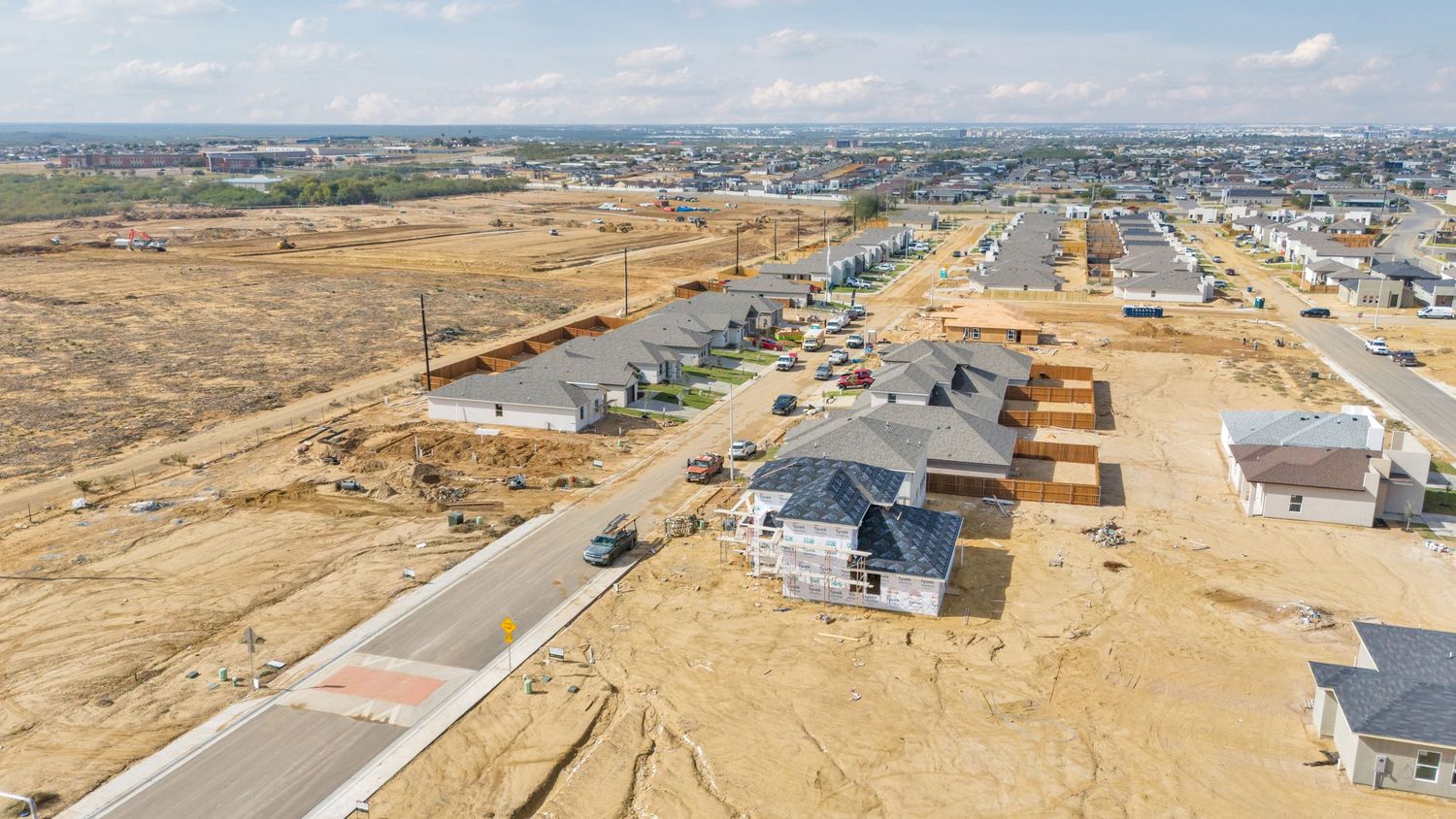 Aerial panoramic view of a suburban residential development with houses and streets stretching to the horizon.