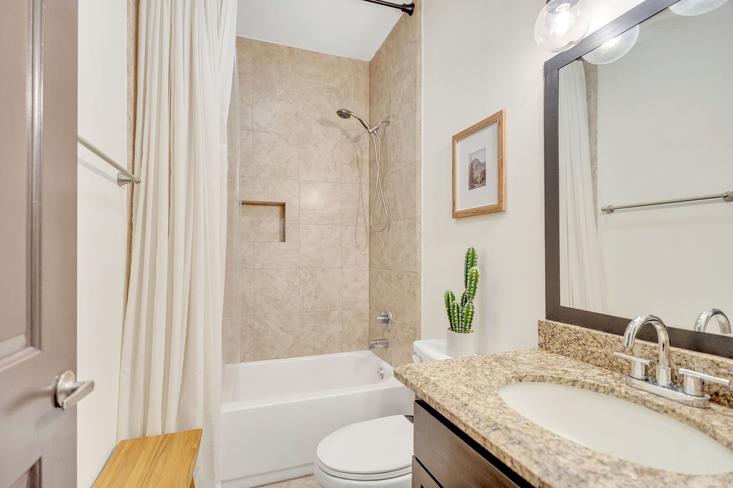 Contemporary bathroom featuring granite countertops, beige walls, and modern fixtures with white accents.