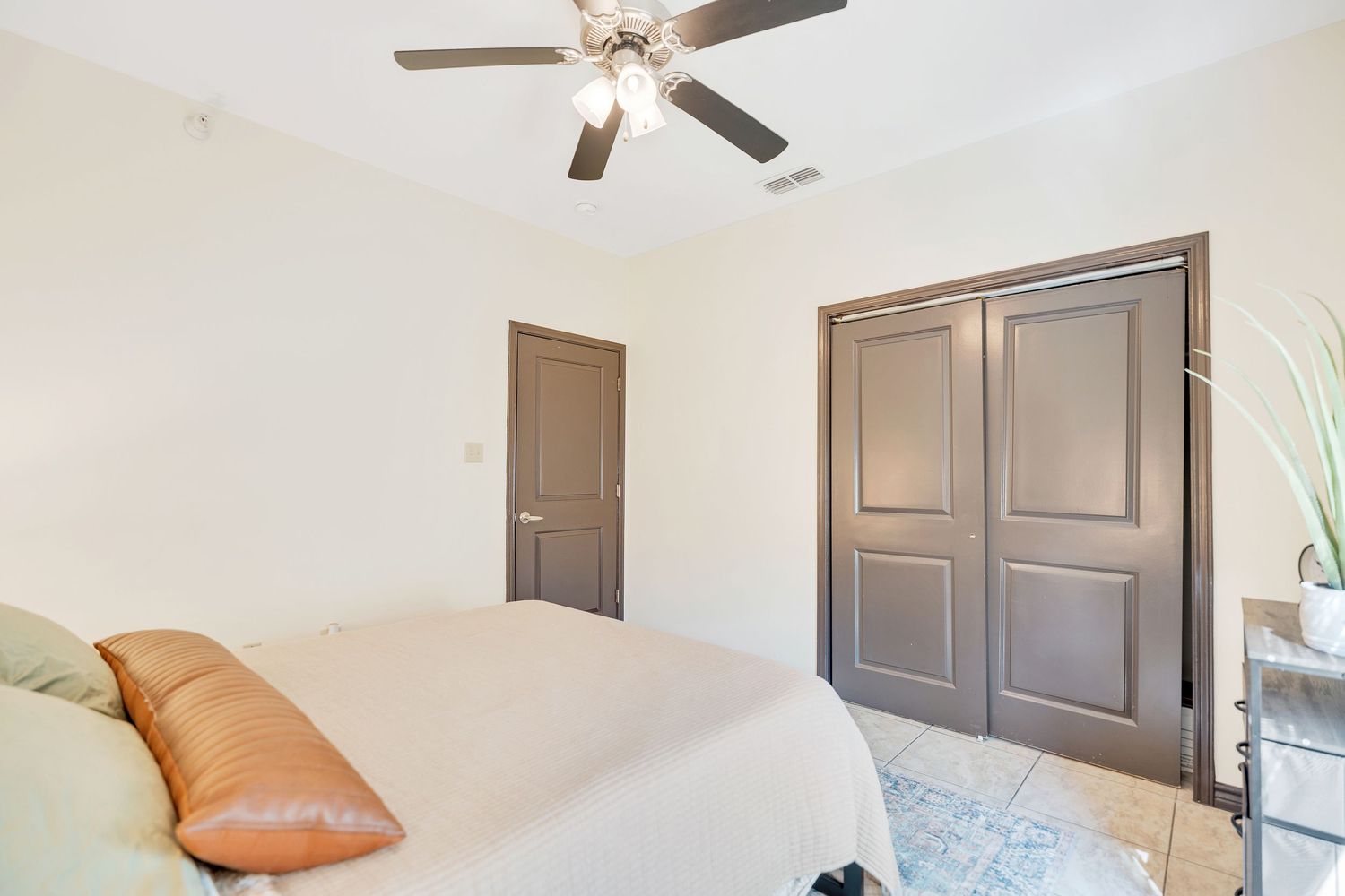 Empty bedroom with ceiling fan and white walls showcasing ample natural light.