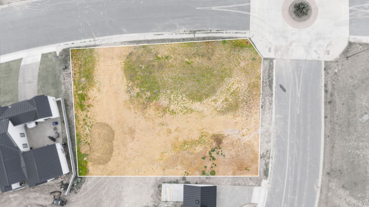 Aerial drone view of a black and white highway intersection with surrounding landscaping and buildings.