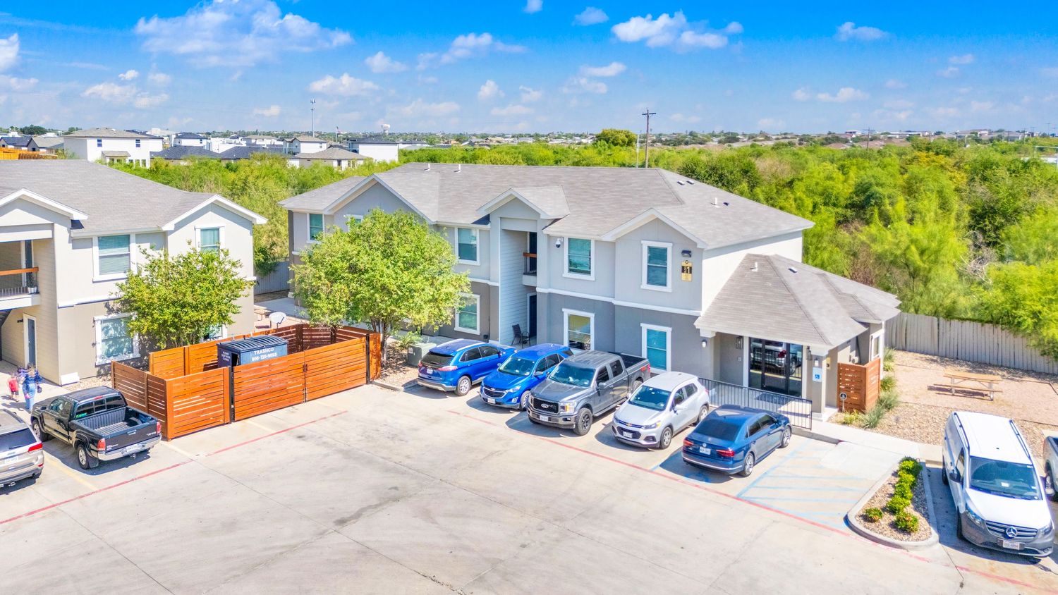 Panoramic aerial view of a mobile home community with parked cars and blue skies on a sunny day.