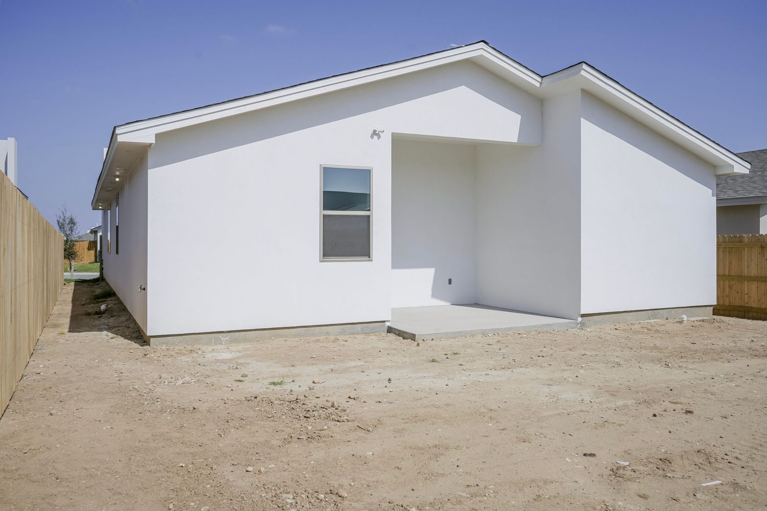 Modern white house with angled roofline and minimalist window design.
